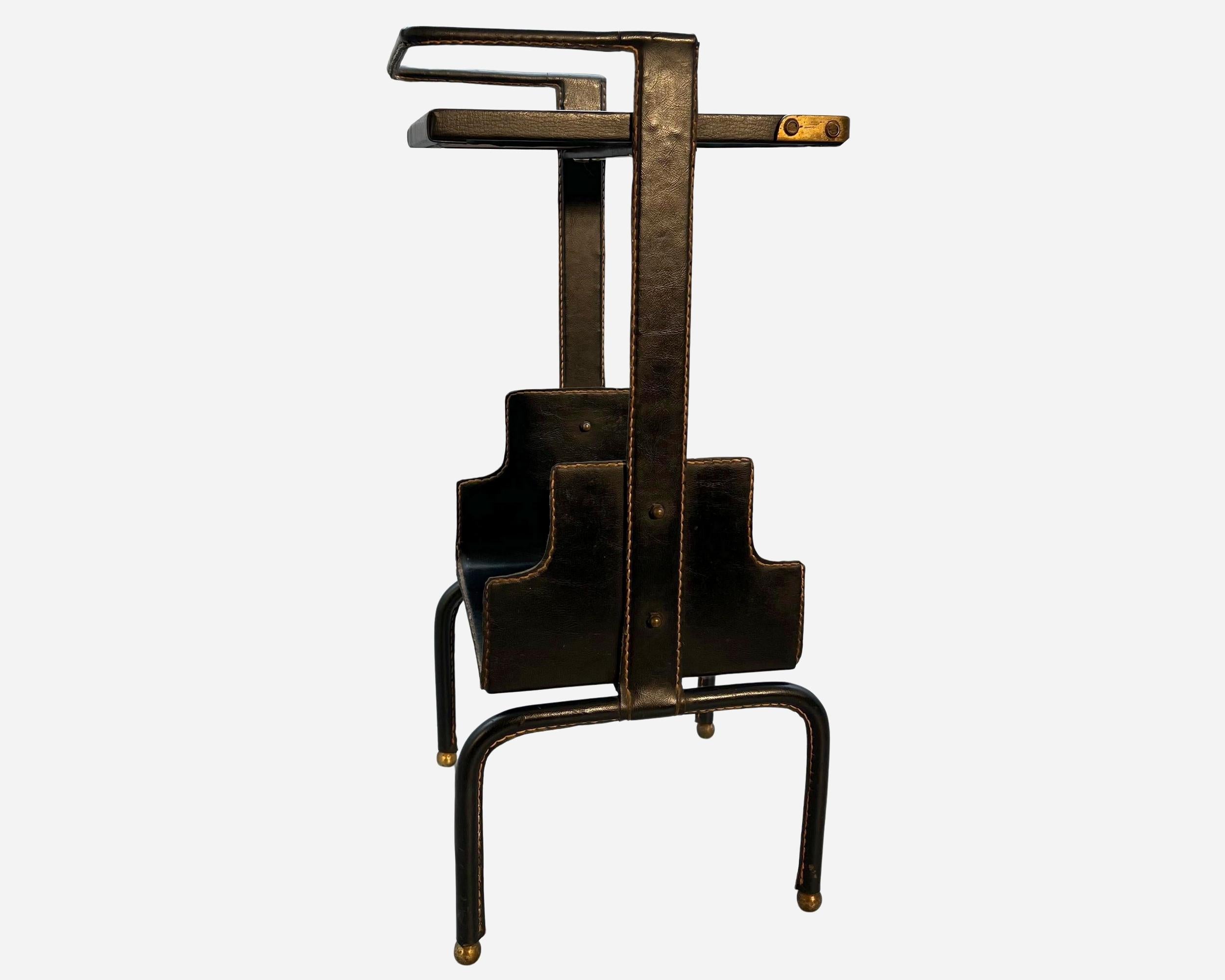 Small occasional (telephone) table by Jacques Adnet (1900-1984) with metal structure entirely upholstered in black saddle-stitched leather, featuring two superimposed tops.
The corners of the top are protected by gilded brass corners. The four legs