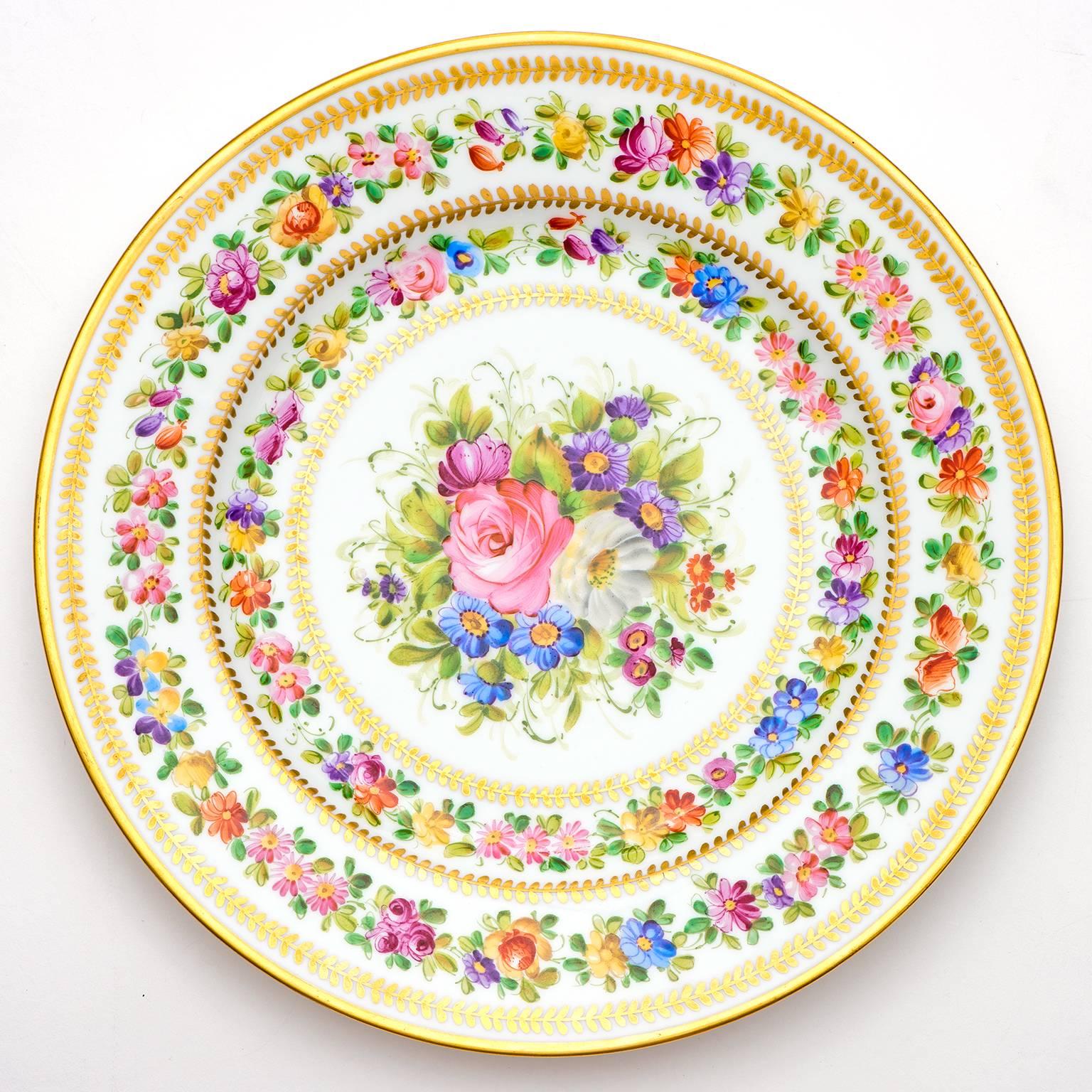 Circa 1890s, decorated by Charles J. Ahrenfeldt, Limoge, France.  These hand-painted service plates by Charles Ahrenfeldt are nothing short of awe-inspiring. Their vividly colorful bouquets are surrounded by wreaths of flowers and gold. The skillful