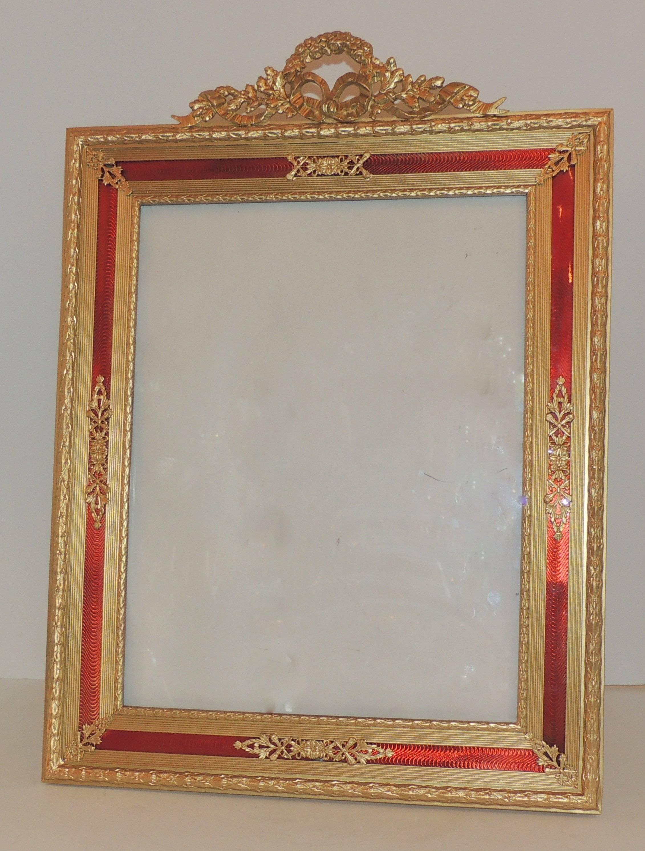 A fine French Louis XVI bronze and red guilloche.
Enameled picture frame with
wreath and ribbon crest, easel back.

Measures: 16 3/4" H x 13 3/4" W.