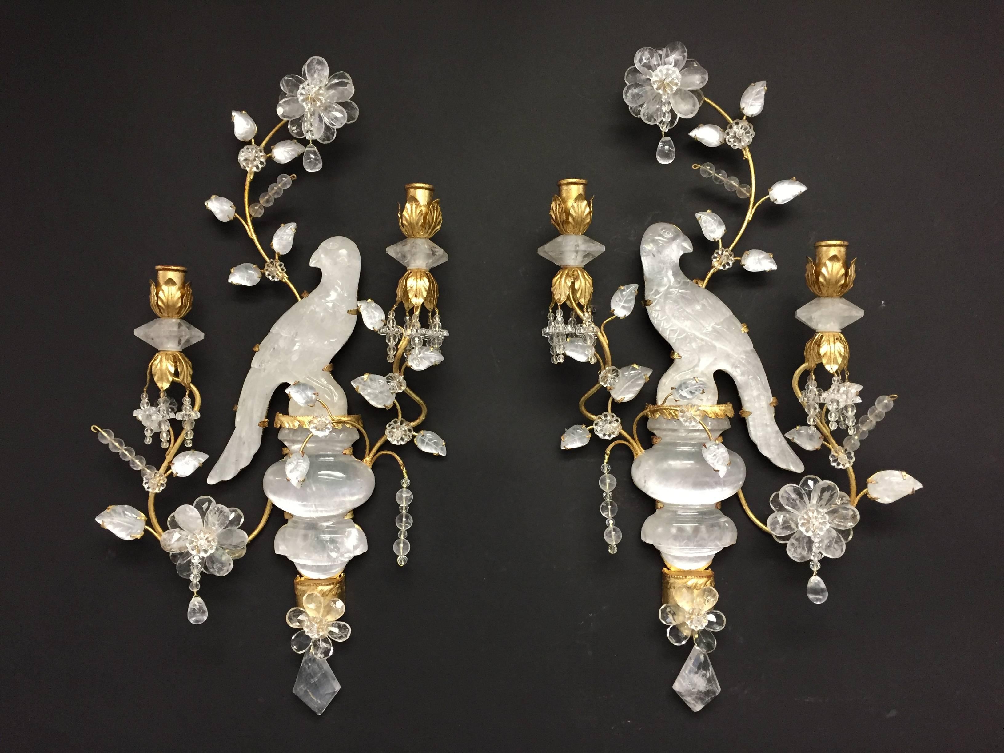 
These endearing Bagues style Vintage two-arm gilt and rock crystal sconces are beautifully balanced with leaves, flowers and the large rock crystal urn the bird is sitting on. Fluted crystal bobeches set off the gilt leaf candle cups sitting next