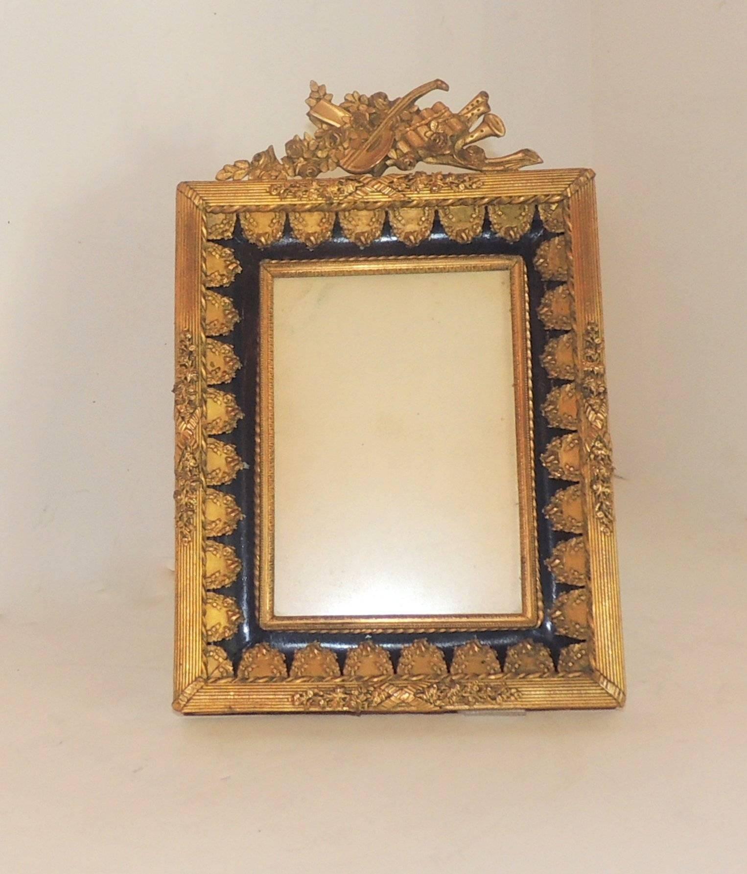 Rich blue enamel and beautifully detailed doré bronze picture frame with musical instruments and floral elements.

Measures: 9.5" H x 6.5" W.
Picture opening: 3.5" x 5.25 (4 x 6 Picture).
