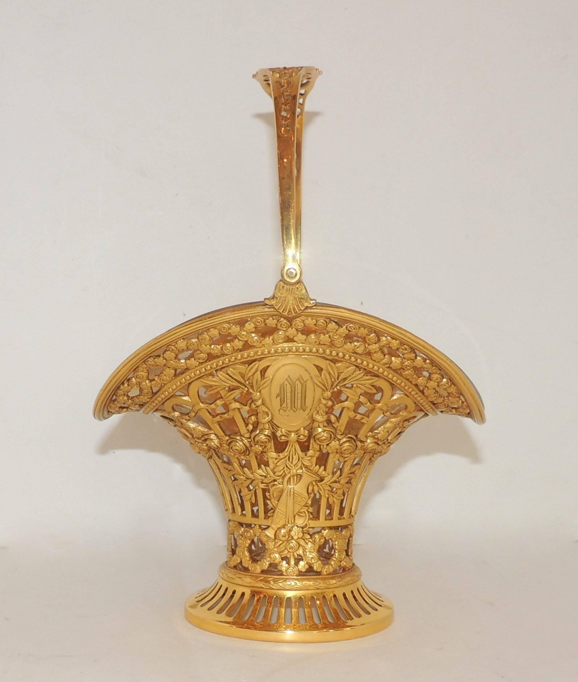 Questo bellissimo cesto traforato in bronzo dorato in stile francese è decorato in modo intricato con rose e festoni. Monogramma M su un lato e sulla parte superiore del manico. Inserto in vetro curvo originale. 
Perfetto per i fiori da sposa, per