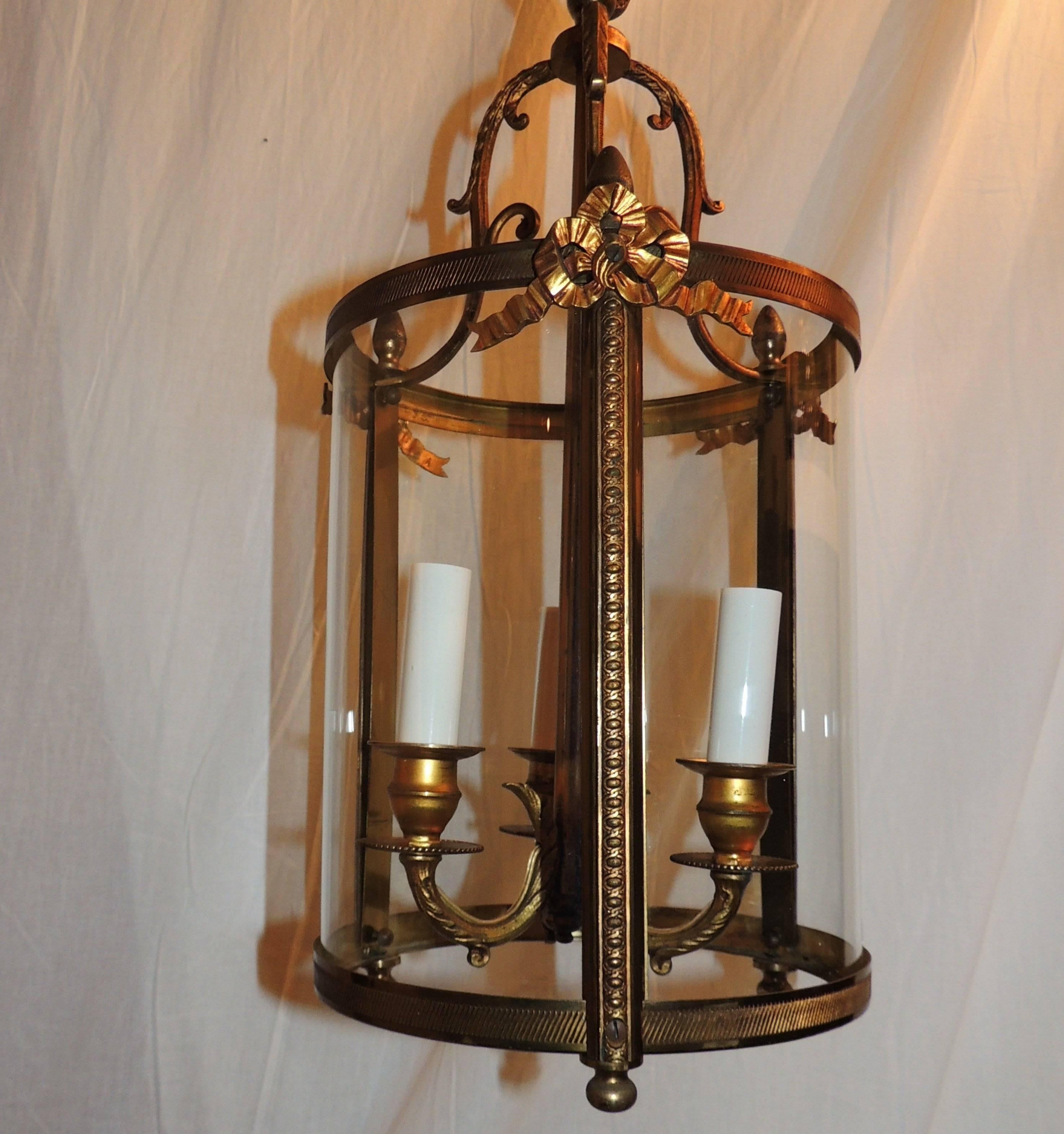 A wonderful petite lantern with curved glass sides and beautiful etched detail from the ribbon bows that accent the top to the filigree decorated arms of the three lights.

Measures: 9