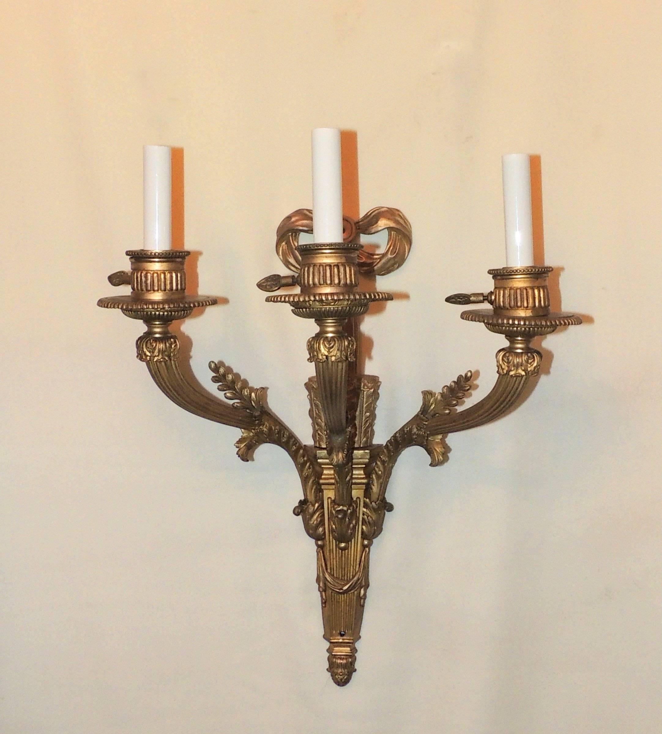 Wonderful three-arm Caldwell doré bronze sconces with ribbon top and filigree details in the Regency style.

Measures: 20" H x 16" W x 9" D.