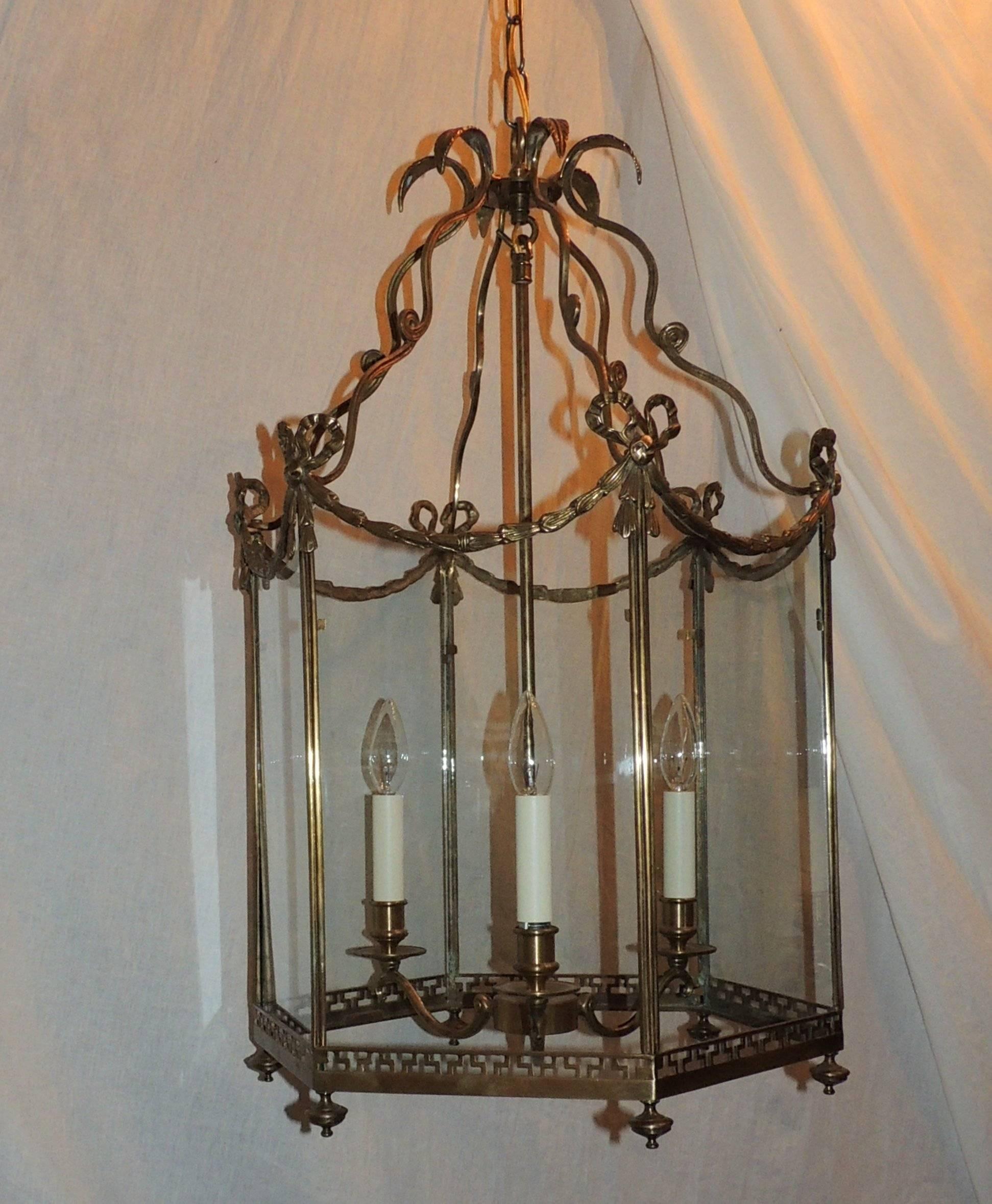 Beautiful etched bronze hexagon shaped lantern, pendent or chandelier fixture with Greek key cutout design around the bottom, fluted edges filigree edges the top edge and ribbon bows highlight the corners.
New wires and sockets.
Measures: 29