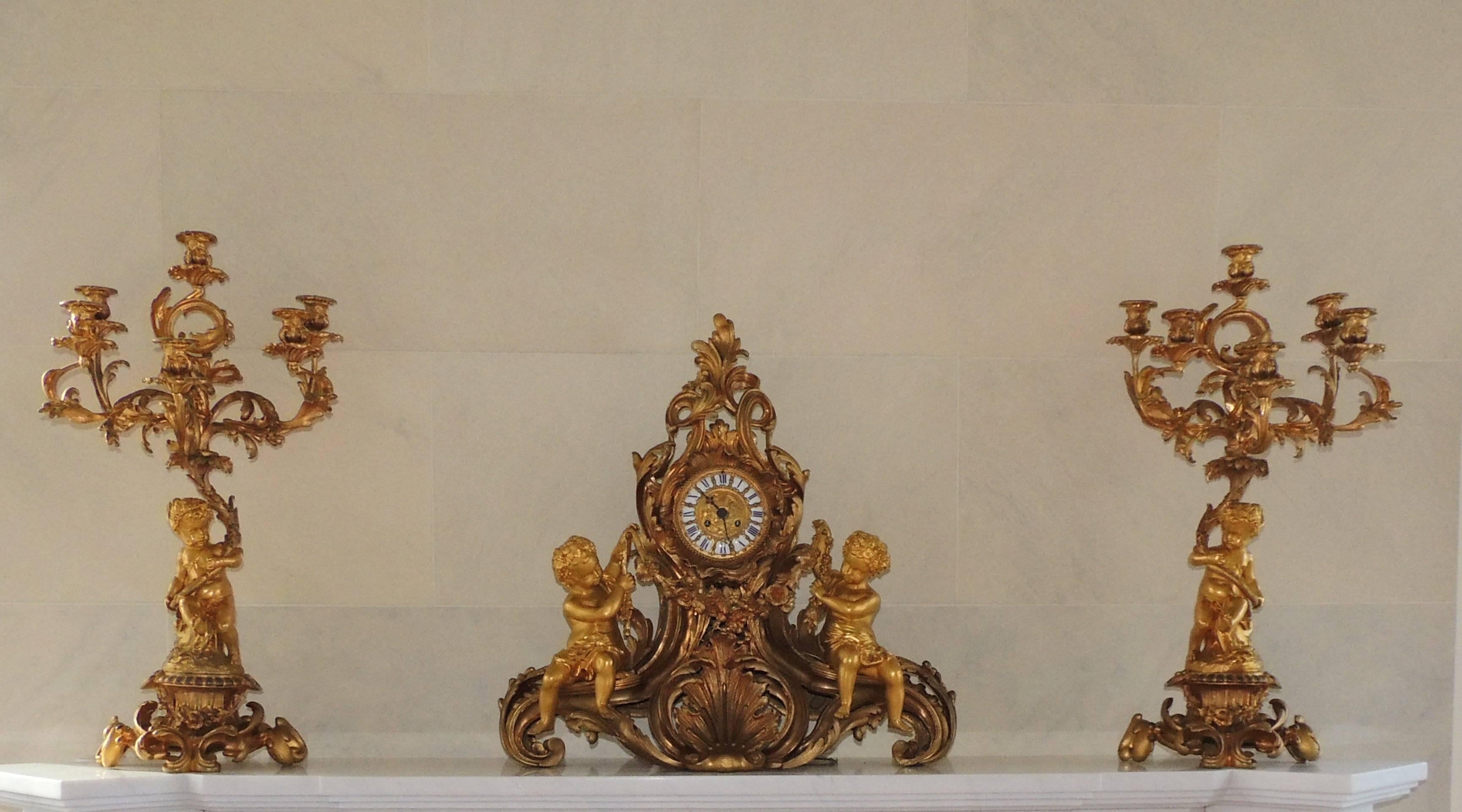 Wonderful large French cherub putti three-piece gilt doré bronze rococo clock set with five-arm candelabras.

Measures: 

Clocks: 26" W x 25" H x 10" D.

Candelabra: 29" H x 15" W x 13" D.