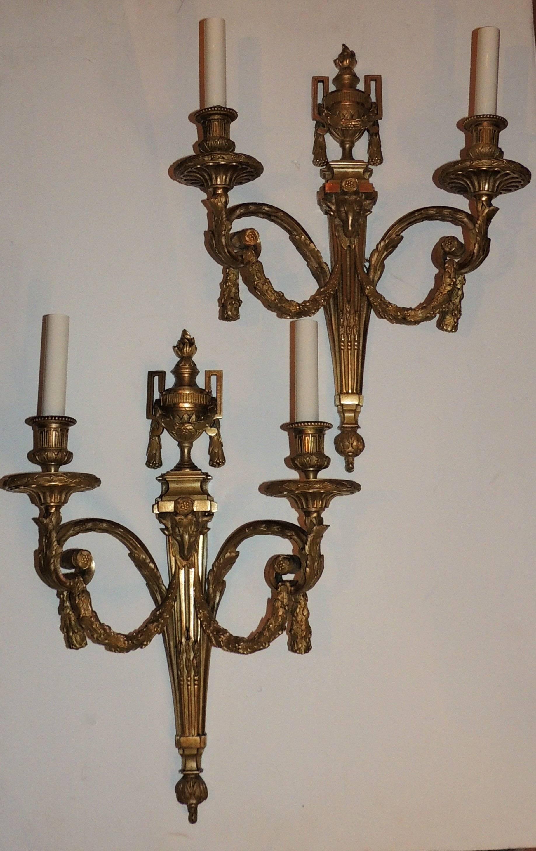 A wonderful Large pair of beautifully etched doré bronze two-arm sconces with filigree draping and swags with fluting detail and decor around the bobeches and a ram's head center medallion of the sconces In the Louis XVI manner.

Measures: 20