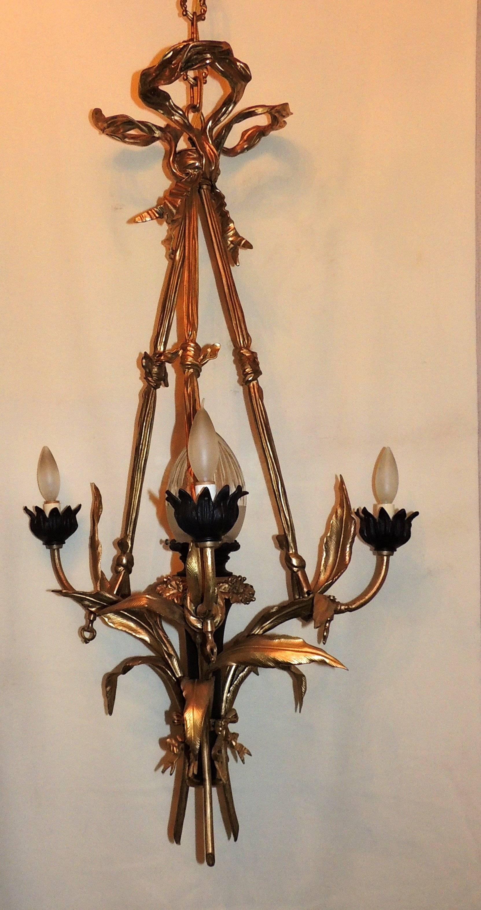 A wonderful French gilt doré and patina bronze bow top neoclassical fixture centered by a crystal shade and three lights surrounding this beautiful chandelier.

Measures: 40