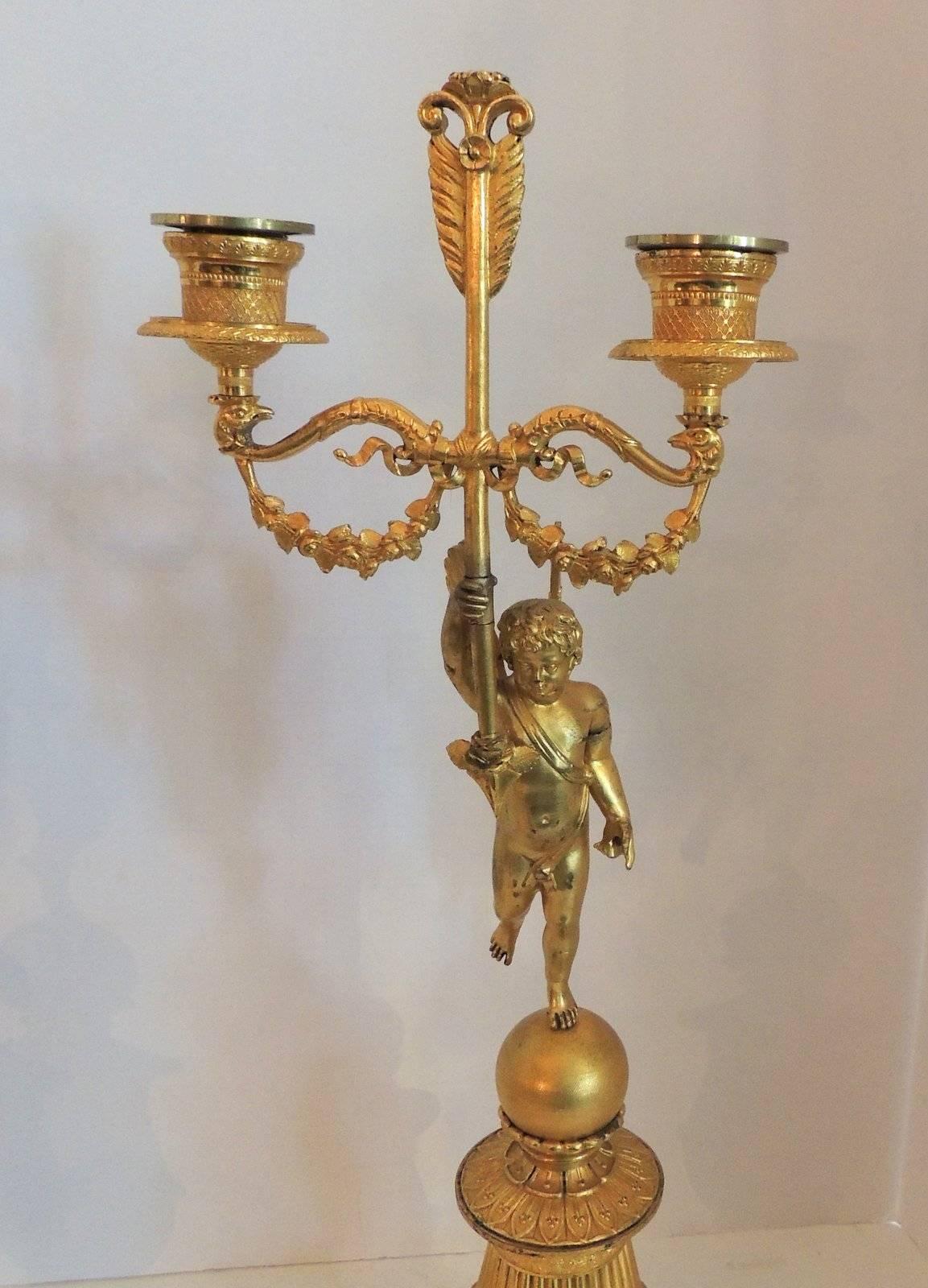 Empire Merveilleuse paire de candélabres néoclassiques à deux bras en bronze doré avec chérubin ailé en vente