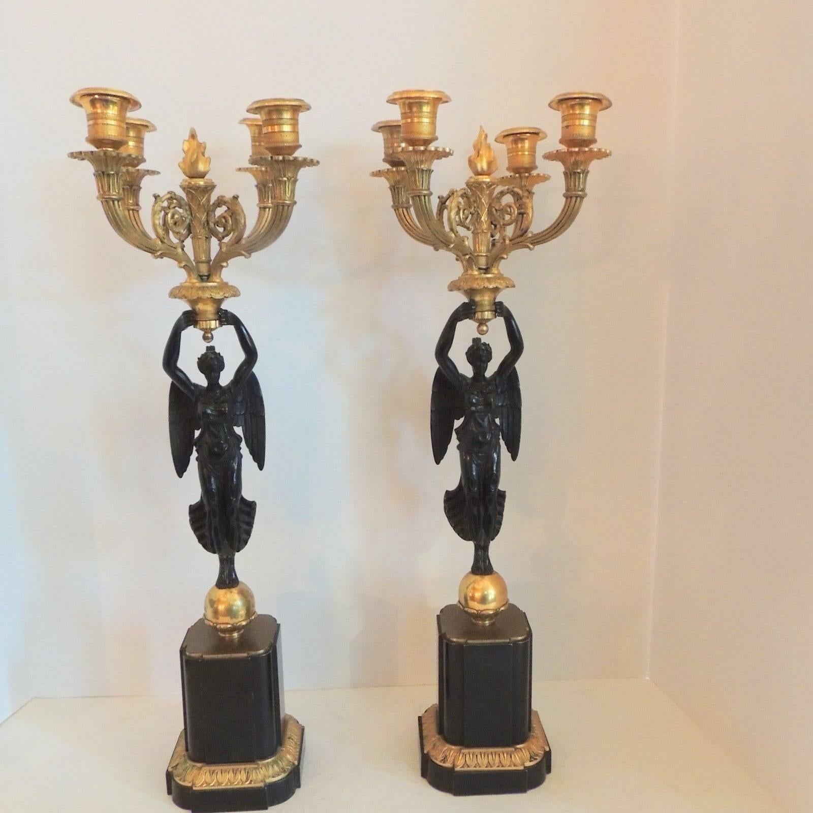 Wonderful pair of French Empire doré bronze four-arm candelabras with a patinated winged woman atop a bronze sphere and decorated pedestal. Wonderful etched details throughout the bronze arms and the center flame.

Measures: 21