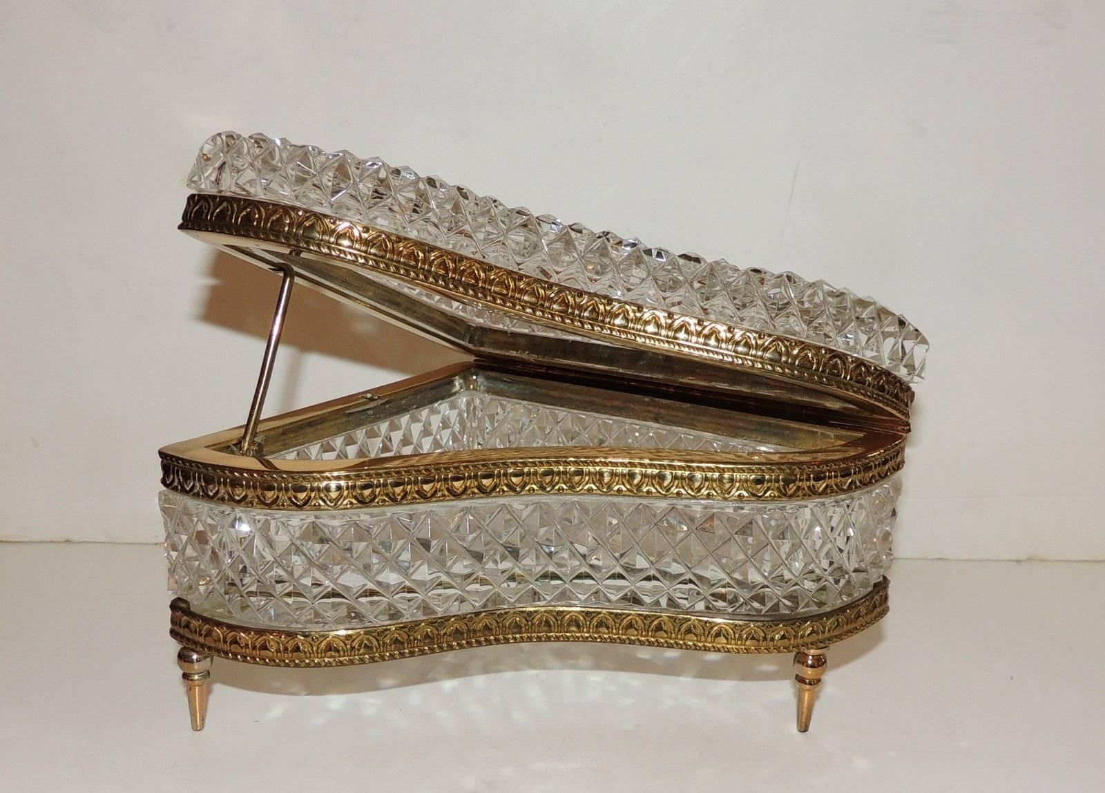 A wonderful French cut crystal box in the shape of a grand piano with gilt doré bronze embossed details and piano arm. Finished with a beautiful star in the bottom crystal.

Measures: 5" W x 5.5" L x 3.75" H.
