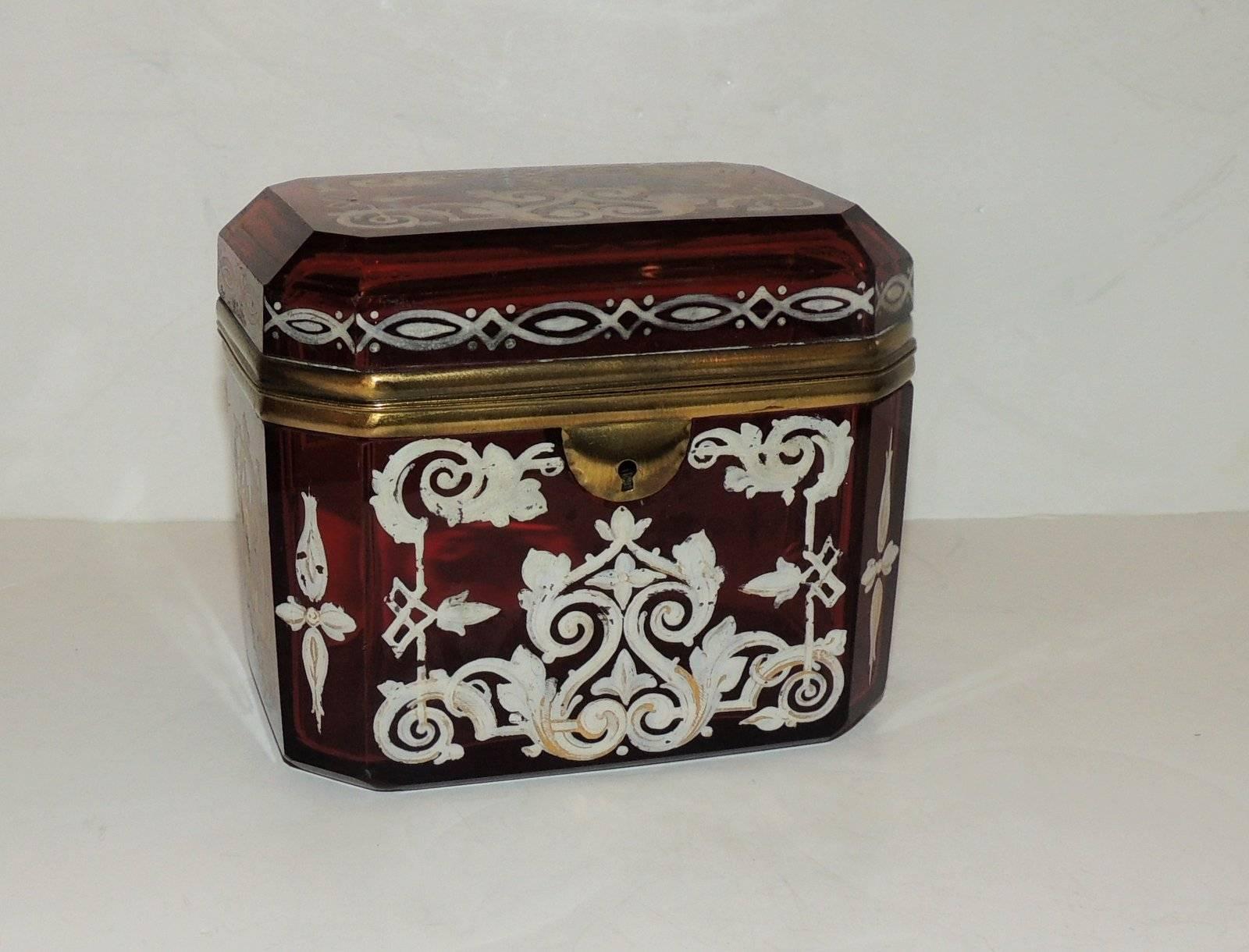 Beautiful rich ruby glass crystal is delicately hand-painted with scroll and floral elements accented with gilt. The sides are a beveled edge which adds to the look of this antique box casket. 

Measures: 4.75" W x 3.5" D x 4" H.