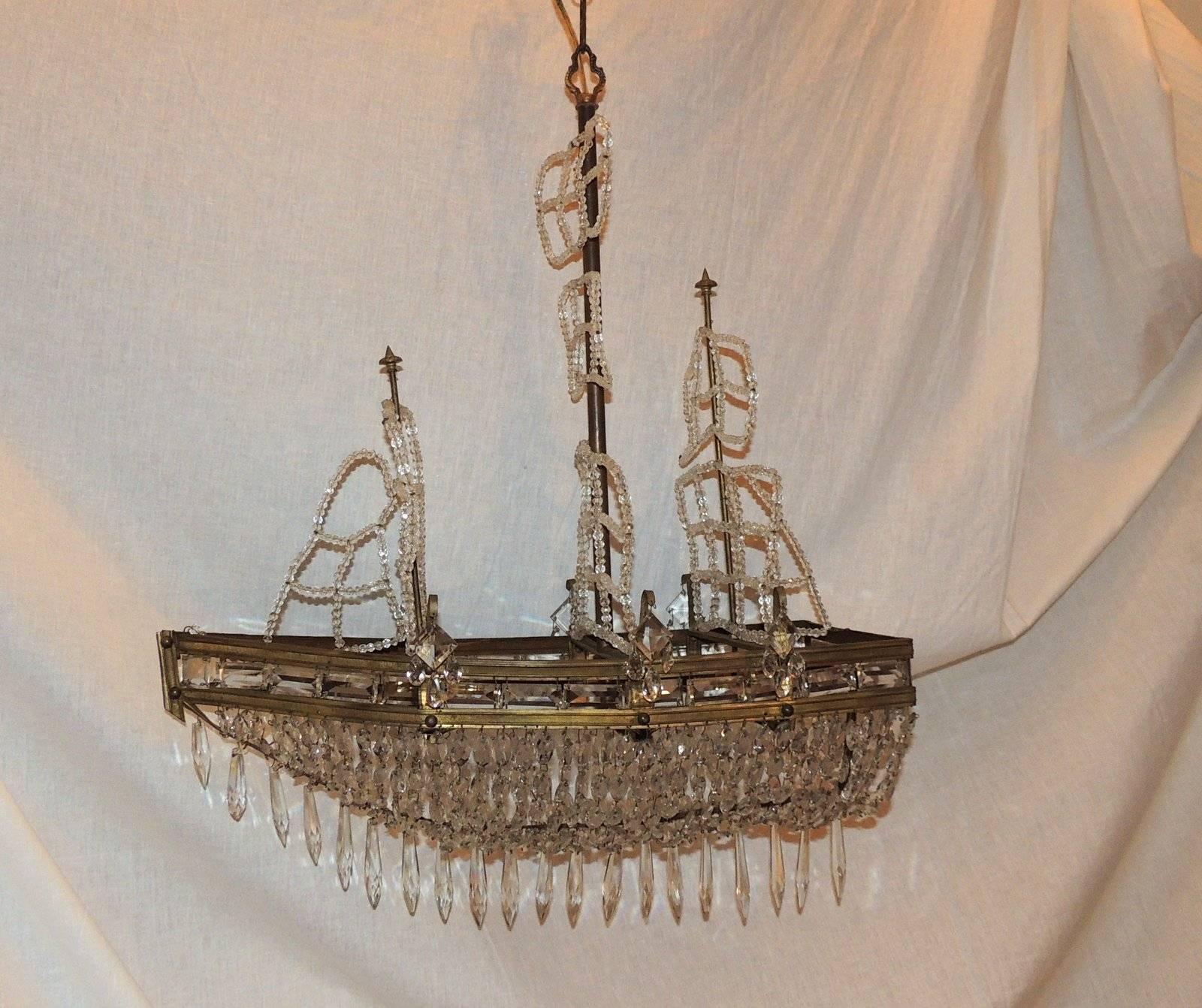 A wonderful sailboat chandelier decorated with etched gilt bronze detail, crystal beaded sails, crystal hull and five interior lights.

Measures: 30" H x 23" W x 11" D.