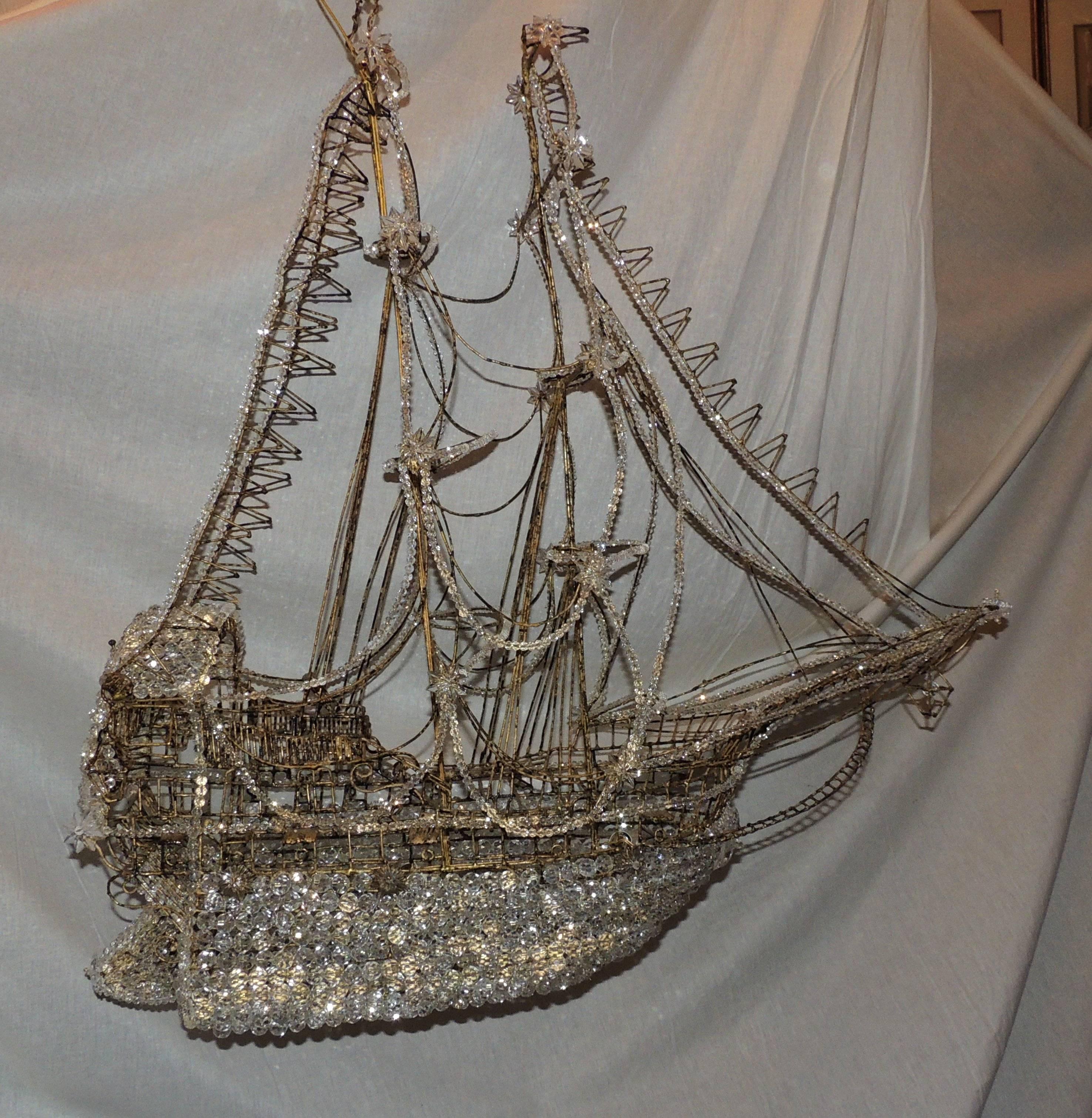 This gilt schooner boat chandelier is beautifully detailed with a crystal beaded keel, crystal star accents and lantern on the bow. Crystal beads highlight the various lines to the top of the ship.
A beautiful addition to any space
This fabulous