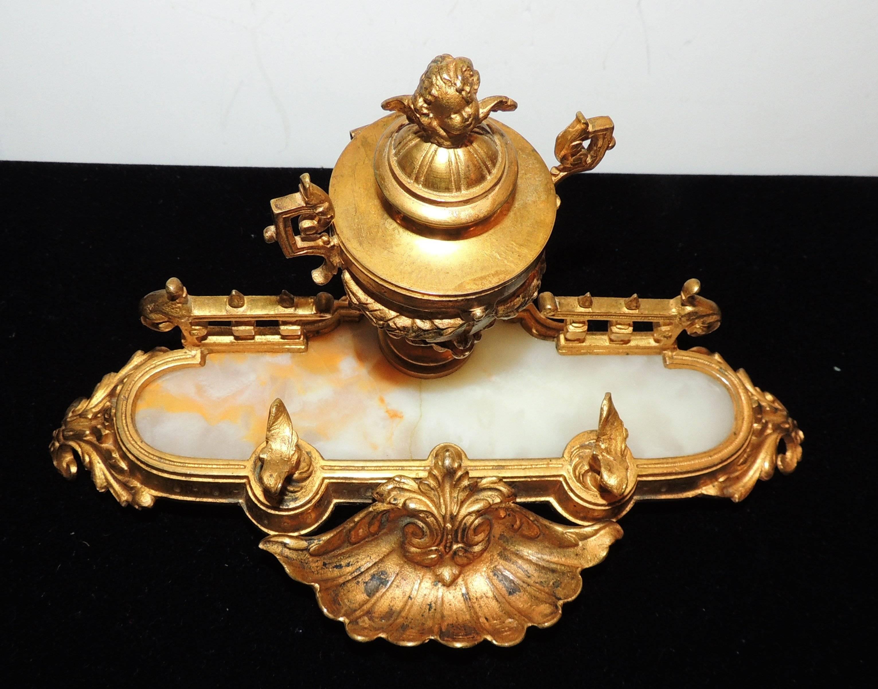 A wonderful French doré bronze inkwell with cherub atop filigree draped urn
Marble insert with pen holder.
  