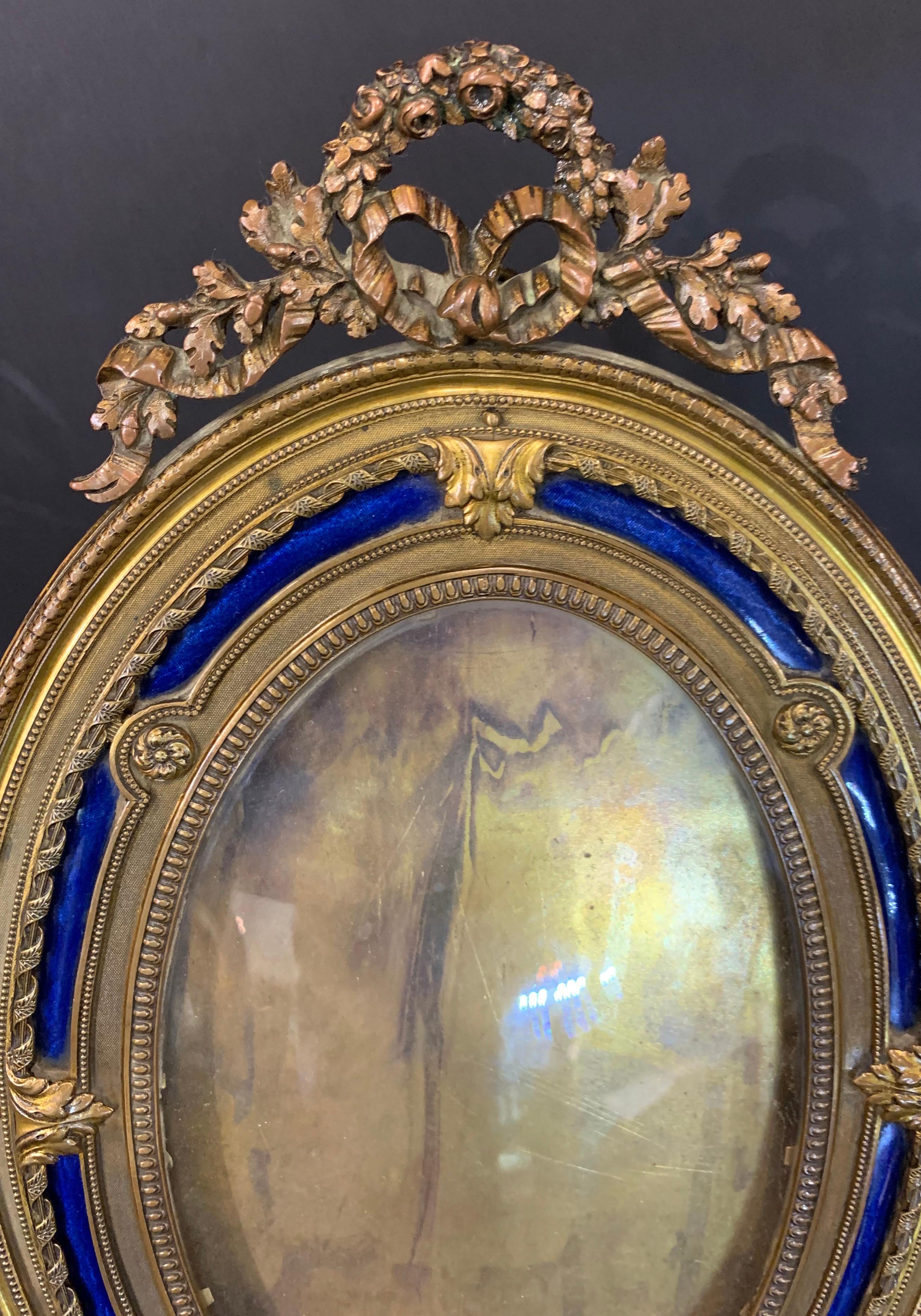 A wonderful French gilt bronze and blue enamel inset oval bow top picture frame.