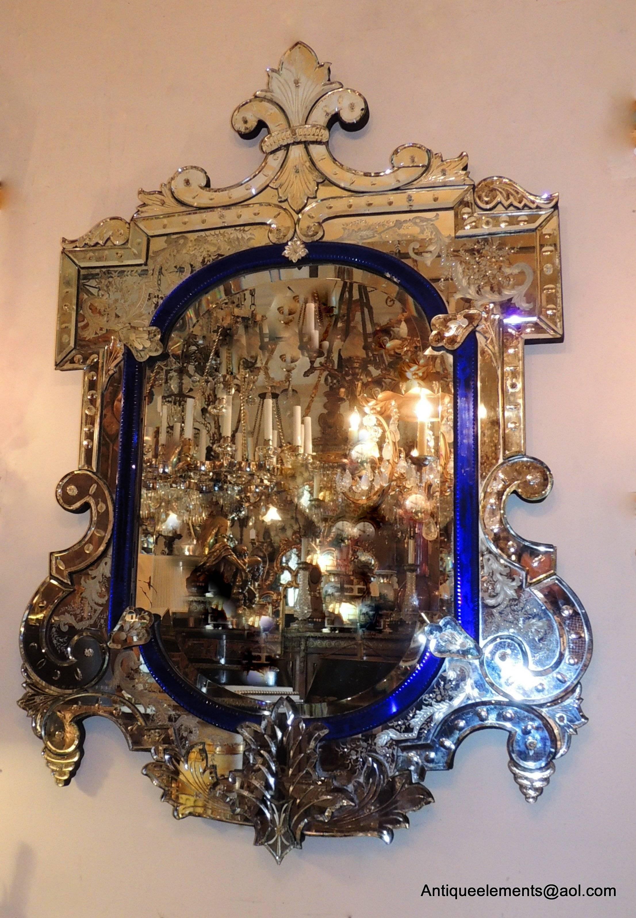 This unusual Venetian mirror is beautifully detailed with wonderful etched elements and scrolls accenting all the edges of this mirror. The striking blue crystal edge framing the beveled mirror finishes this antique Venetian mirror.
Two of the