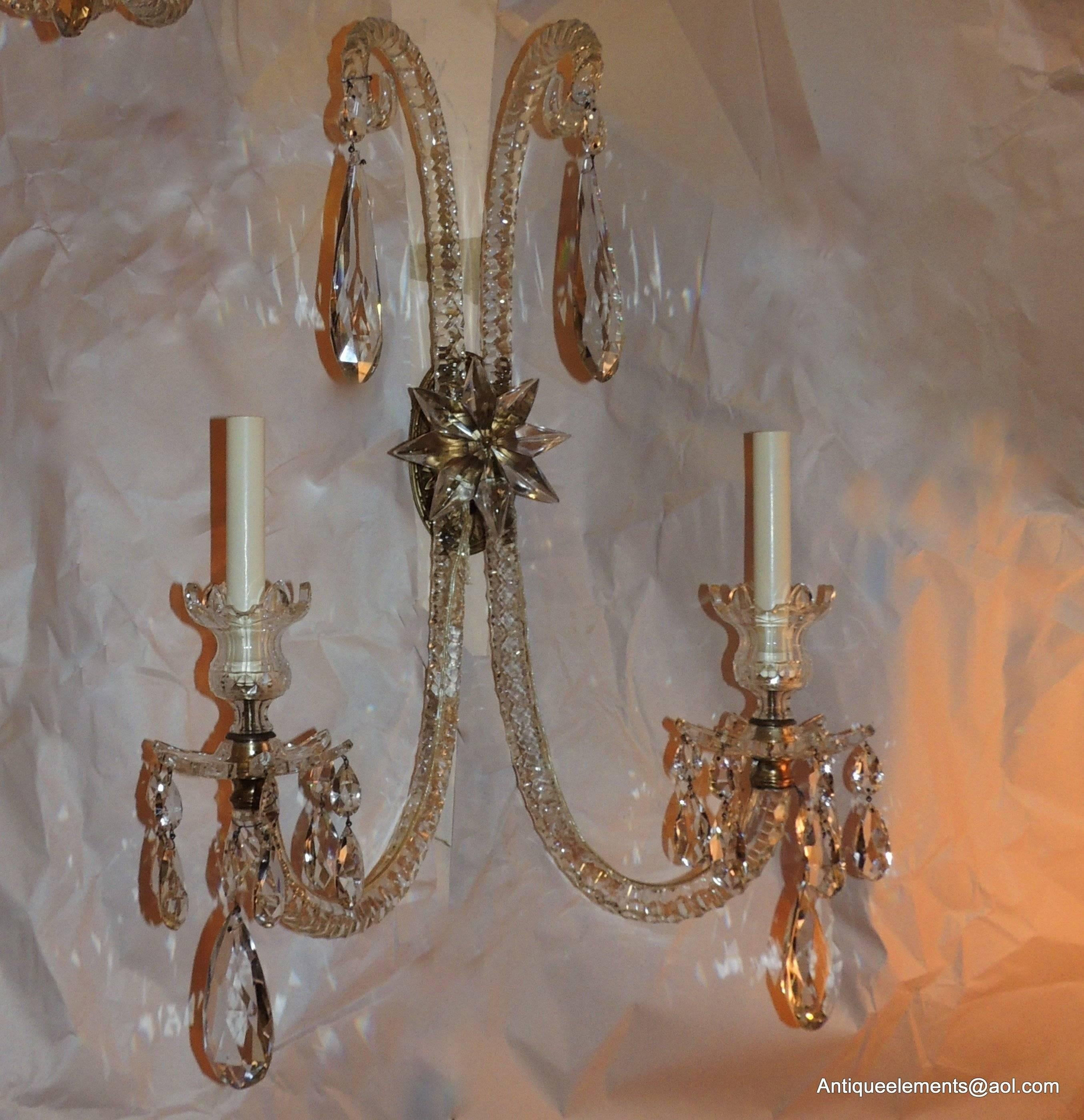 An elegant pair of sconces with beautiful cut crystal and faceted arms and prism drops and a doré bronze floral back center medallion and finished with a large cut crystal star. These large sconces are 26