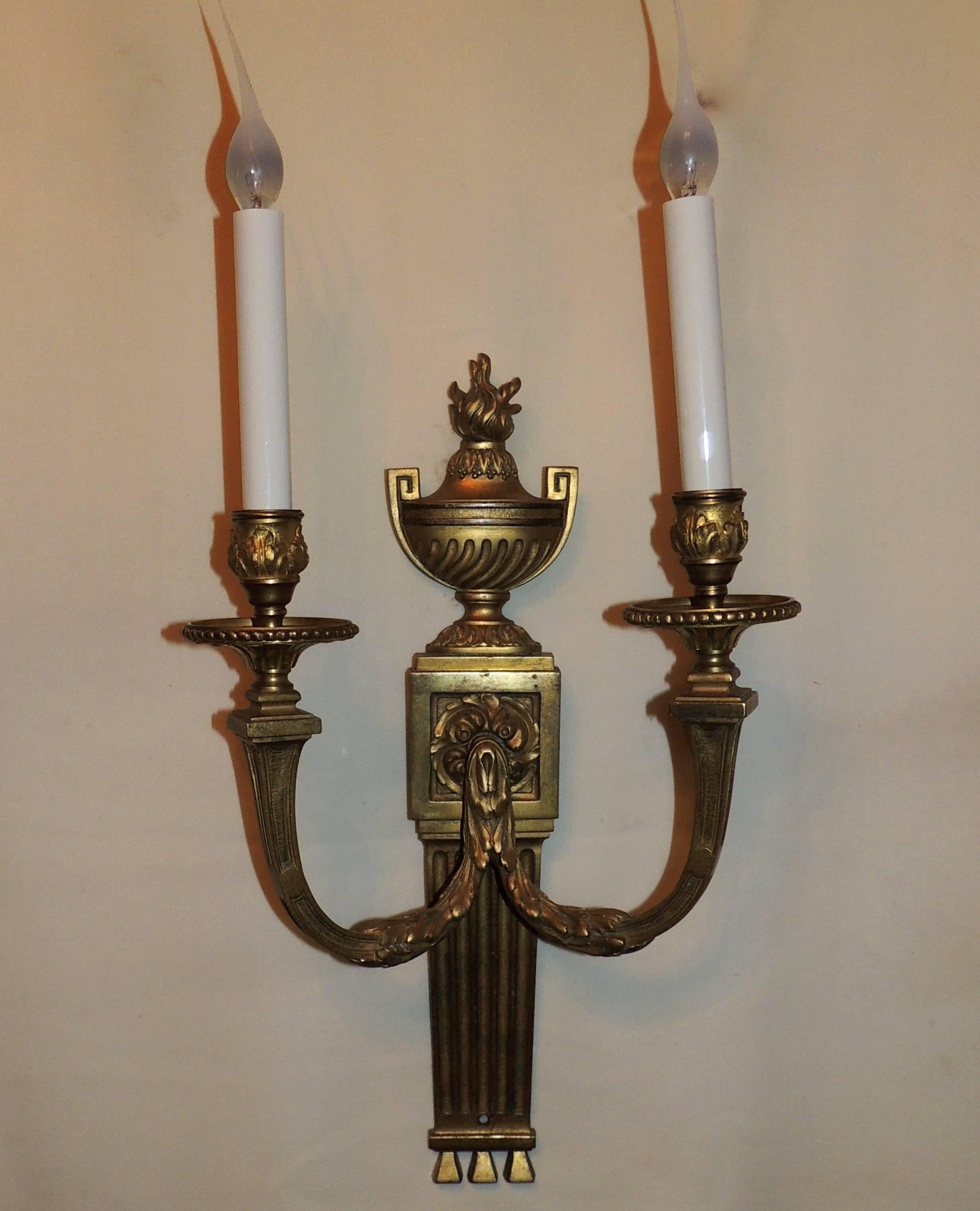 This wonderful elegant pair of doré bronze two-arm sconces by E. F. Caldwell Co. are beautifully decorated throughout. From the urn and flame at the top to the rosette in the mid section, the fluted detail on the underside of the cups and the