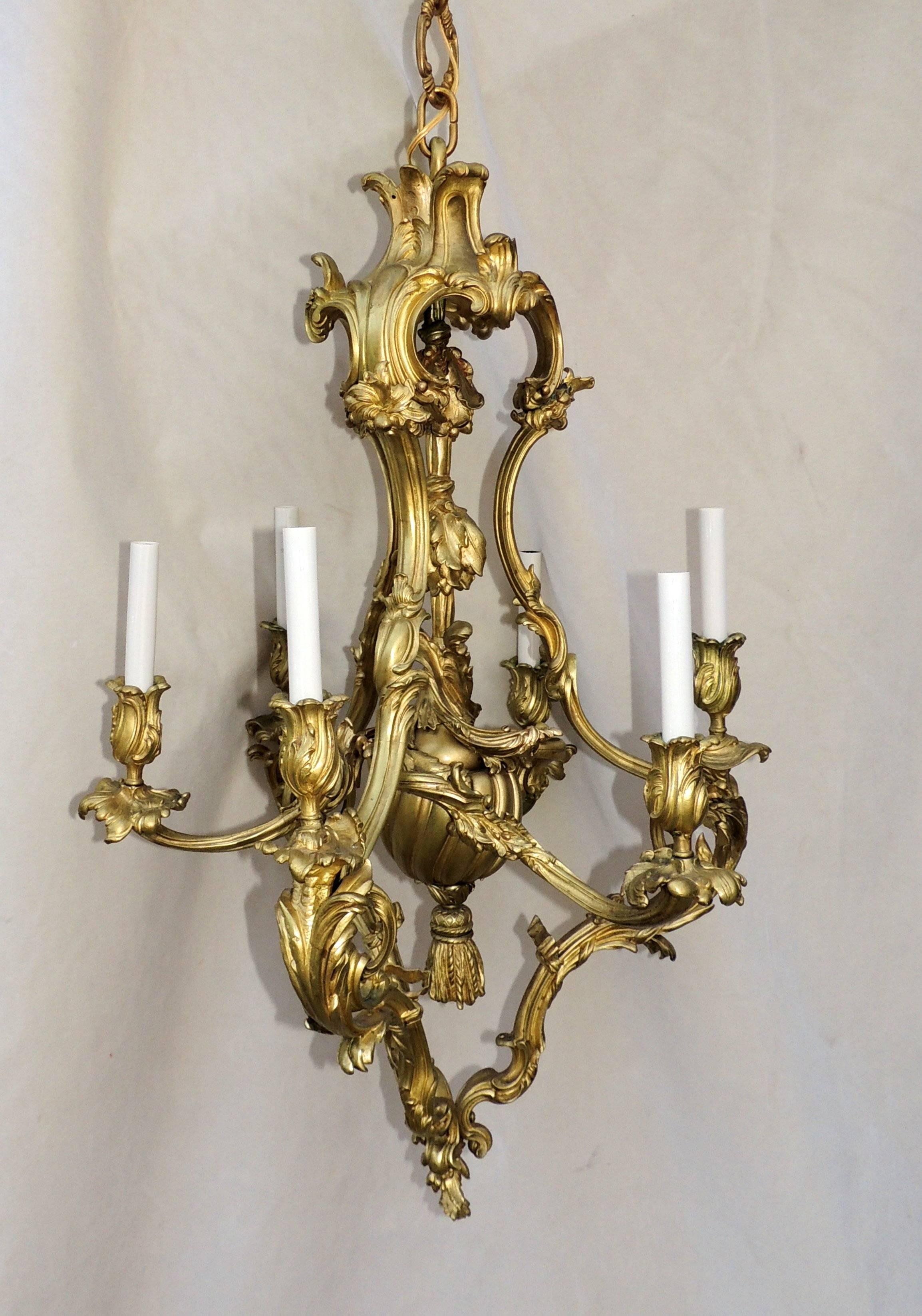 Beautiful leaves envelope the six candle cups and are gracefully layered throughout this large Rococo doré bronze chandelier with tassel accented center.

Measures: 38