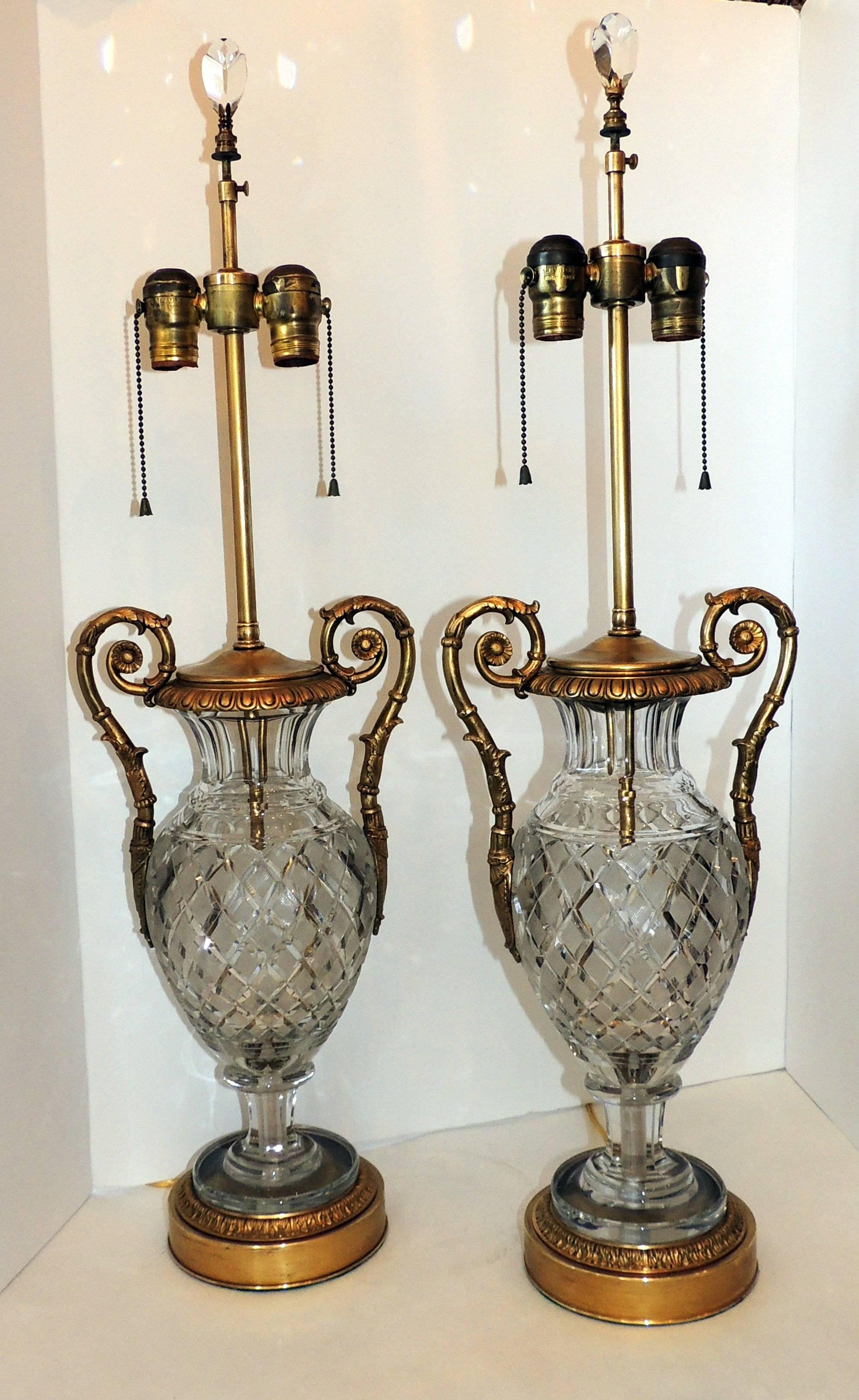 Beautiful pair of leaded cut crystal urns with etched body and fluted top sitting on graduated crystal pedestal. Doré bronze ormolu filigree handles along the sides and bronze ormolu base and crystal finials finish these wonderful neoclassical