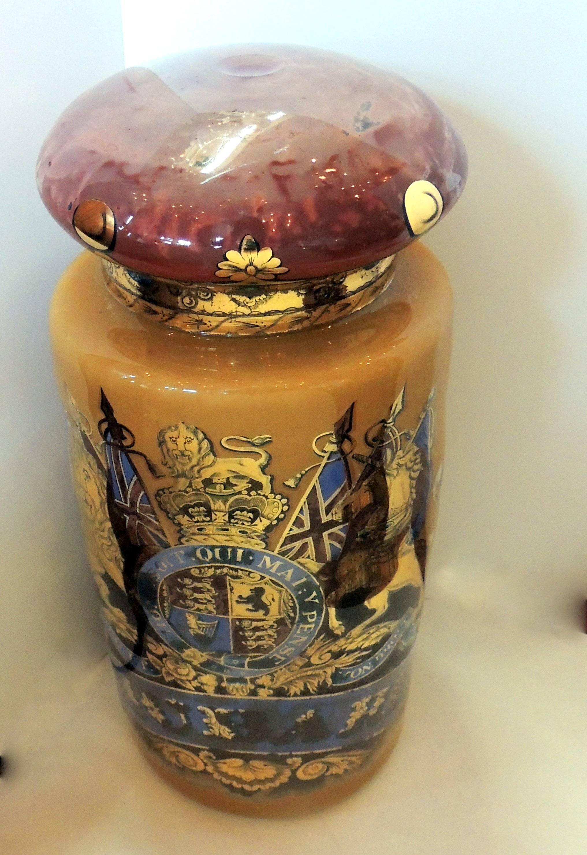 Vintage pharmacy blown glass apothecary jar reverse hand-painted.

Gold colors with flags, lion and unicorn. Top is red color with gilt leaves surrounding edge.

