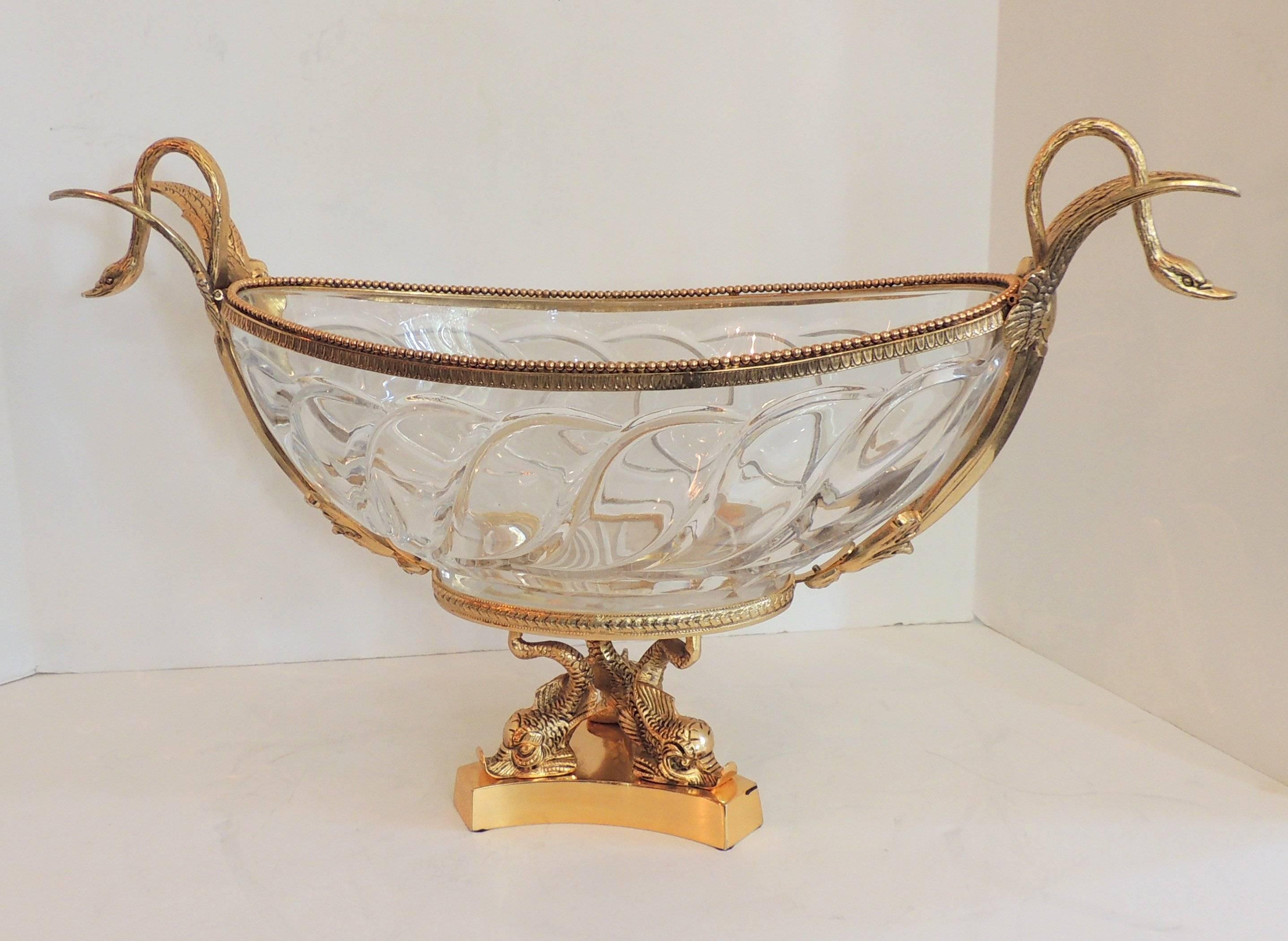 Wonderful doré bronze centerpiece with three dolphins on the pedestal and two lovely swans in flight on each side. The wavy crystal insert with star burst bottom add to the elegance of this impressive centerpiece.

Measures: 14