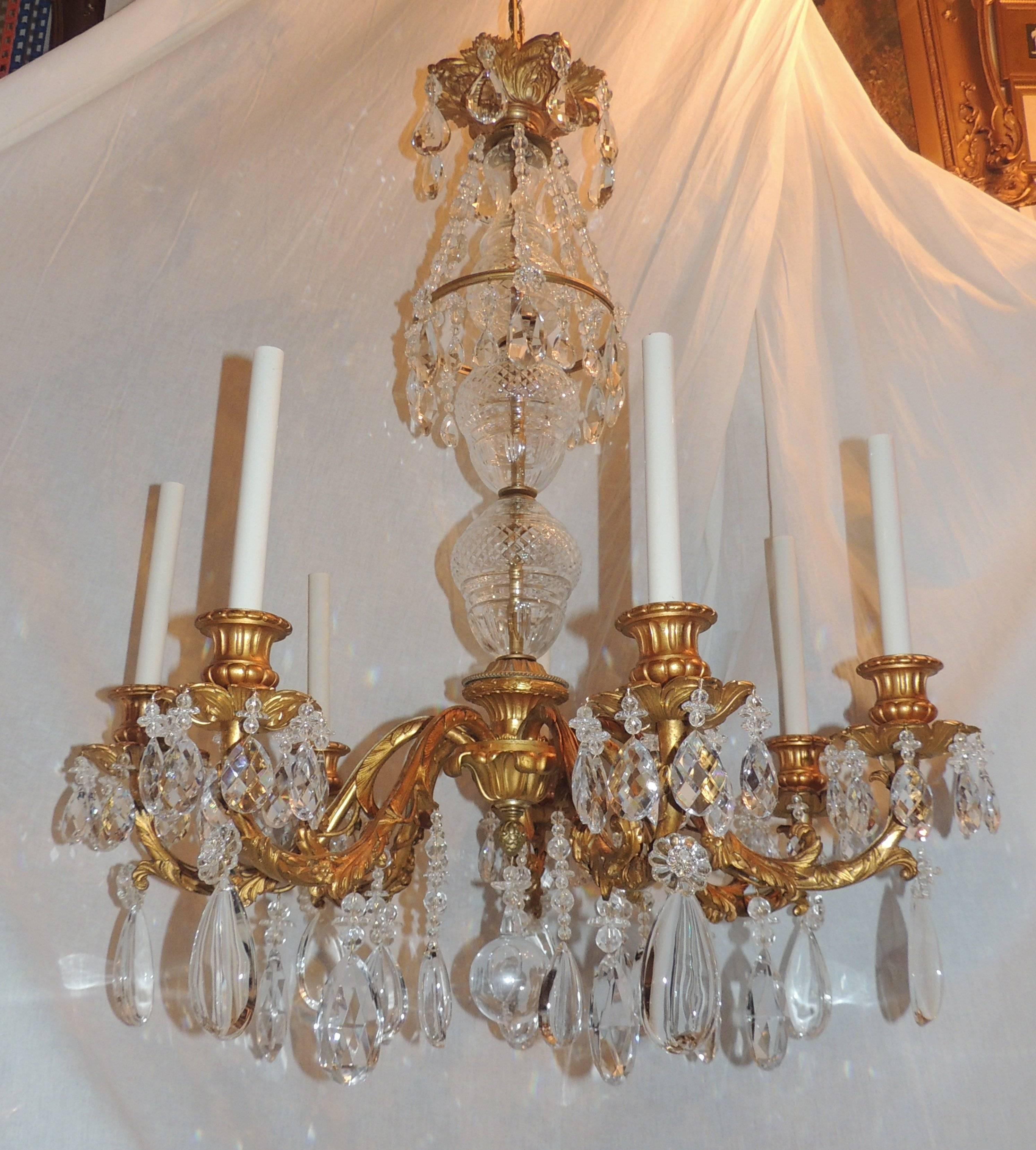This elegant gilt bronze chandelier has wonderful cut crystal center with seven filigree detailed arms finished with fluted candle cups sitting atop floral bobeches. The crown is draped with crystal drops and flowers and finished with a beautiful