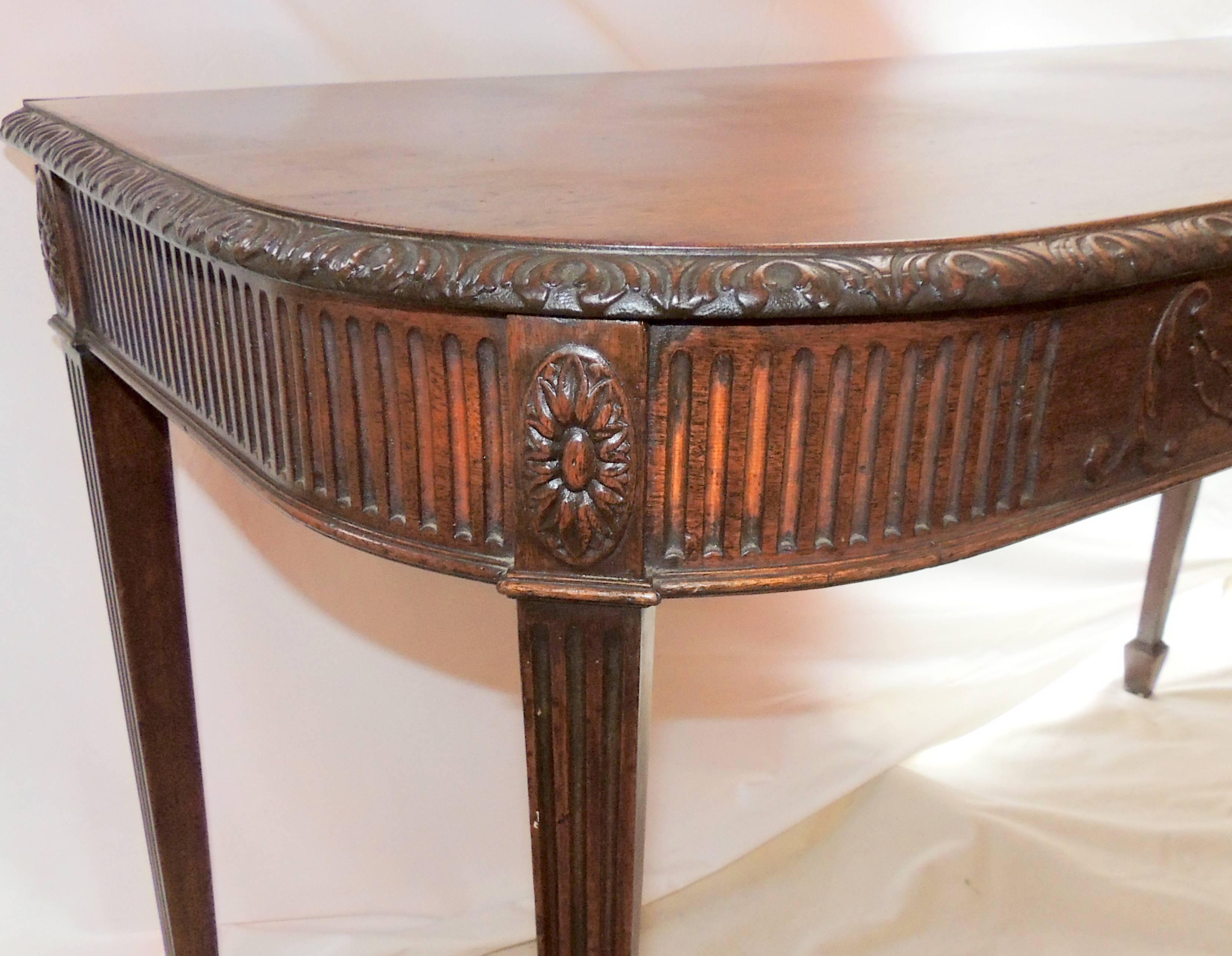 A handsome Federal style pair of carved English console tables or servers in The Duncan Phyfe manner finished with an urn center medallion, and carved border flutted legs.

Measures: 47.5" W x 30.5" H x 22" D.