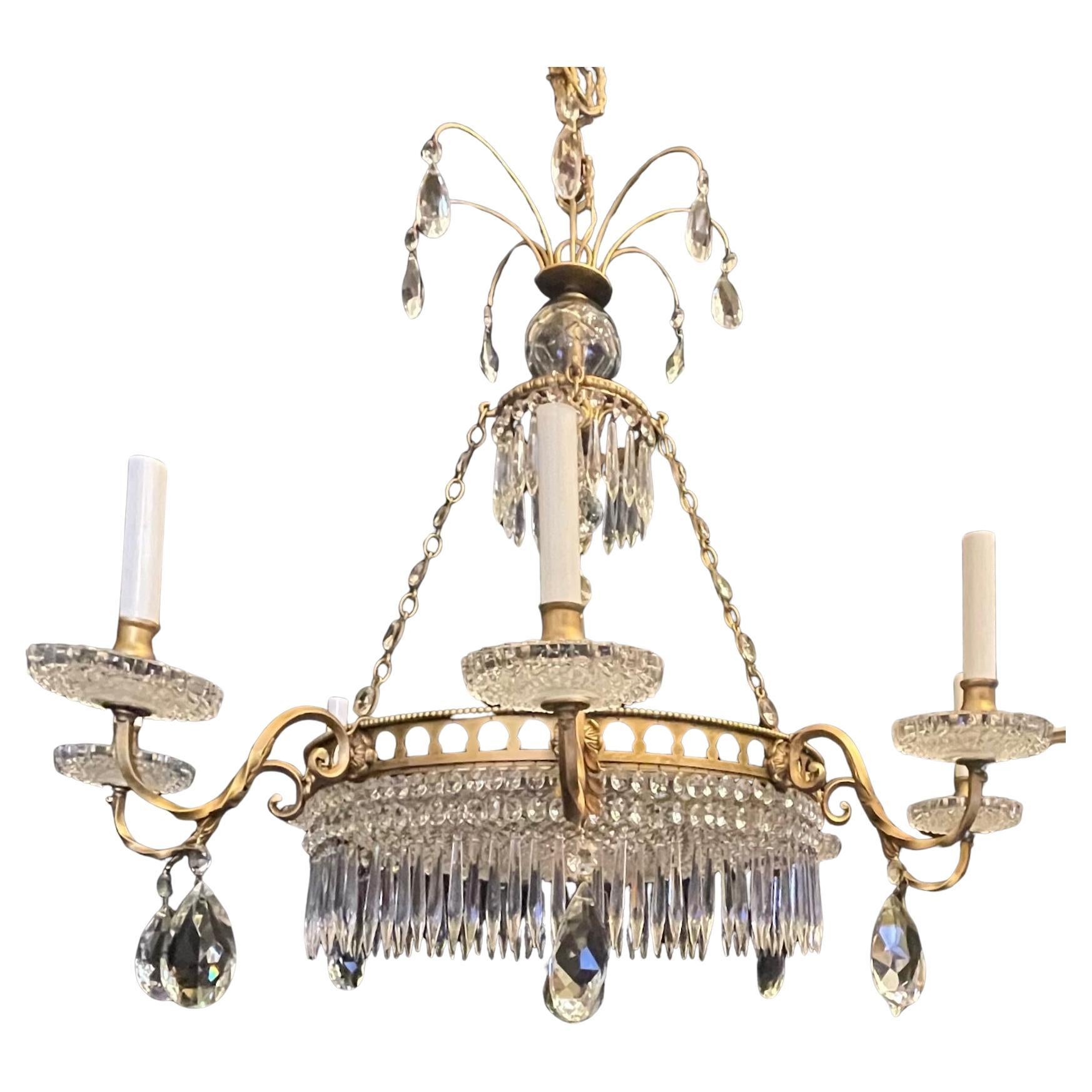 Questo meraviglioso lampadario dorato a 12 luci ha quattro interni e otto bracci decorati con gocce di cristallo e lancia di cristallo che circondano una ciotola centrale in cristallo sfaccettato. I cristalli sono anche intrecciati nella catena, il