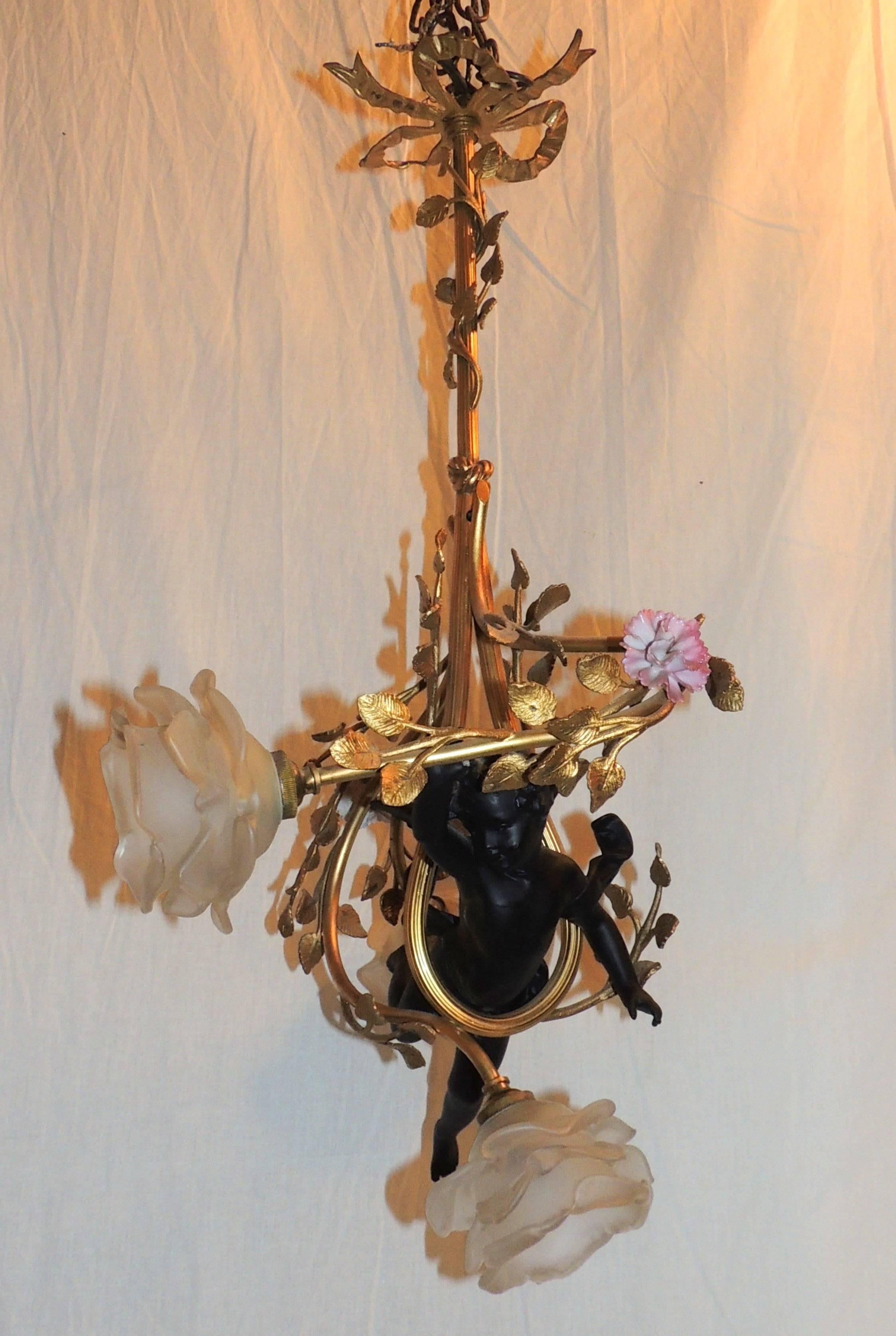 This lovely French doré́ bronze chandelier has branches entwined around the sweet cherub above a branch with three lights. Original frosted flower shades and porcelain flowers accent the leaf decorated branches.

Measures: 24