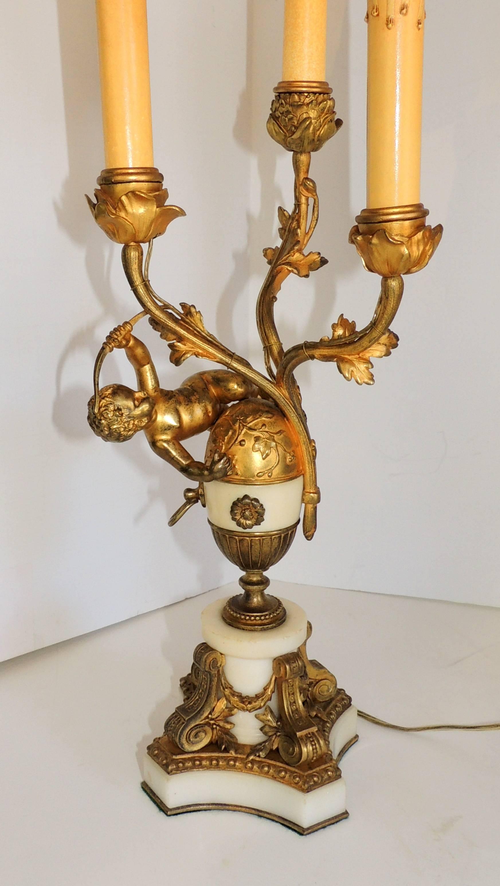 A beautiful pair of French gilt doré bronze and marble cherub ormolu-mounted candelabra / three branch lamps.