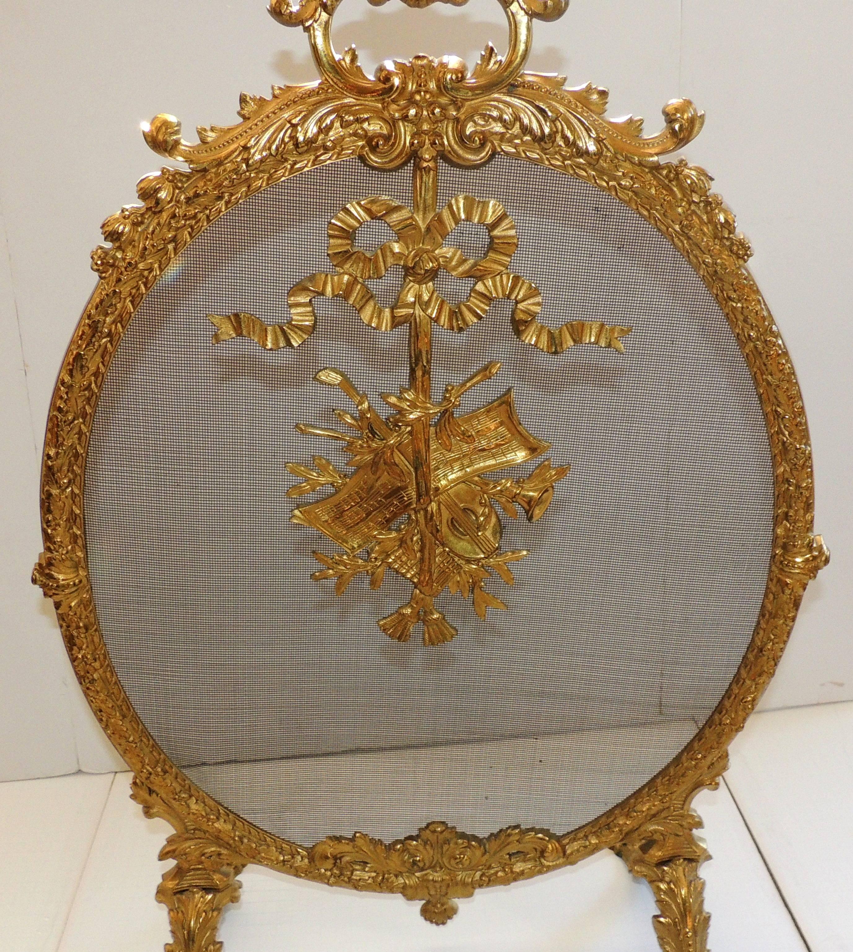 A wonderful French doré bronze oval form ormolu-mounted with basket form and bows with instruments fireplace screen.