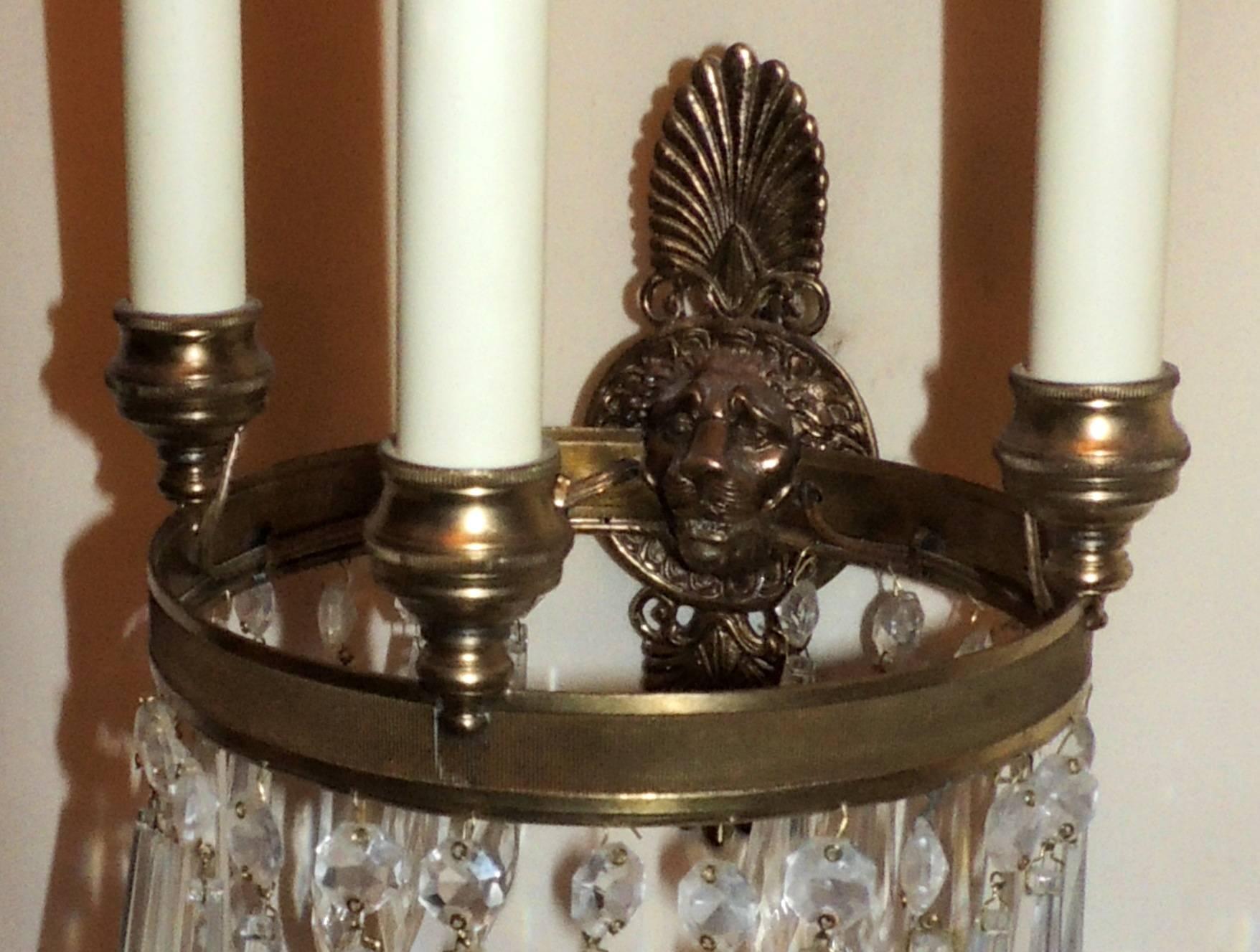 A wonderful pair of French Empire Regency gilt bronze and crystal round ribbed ring sconces with lion head centre medallion and three-lights.