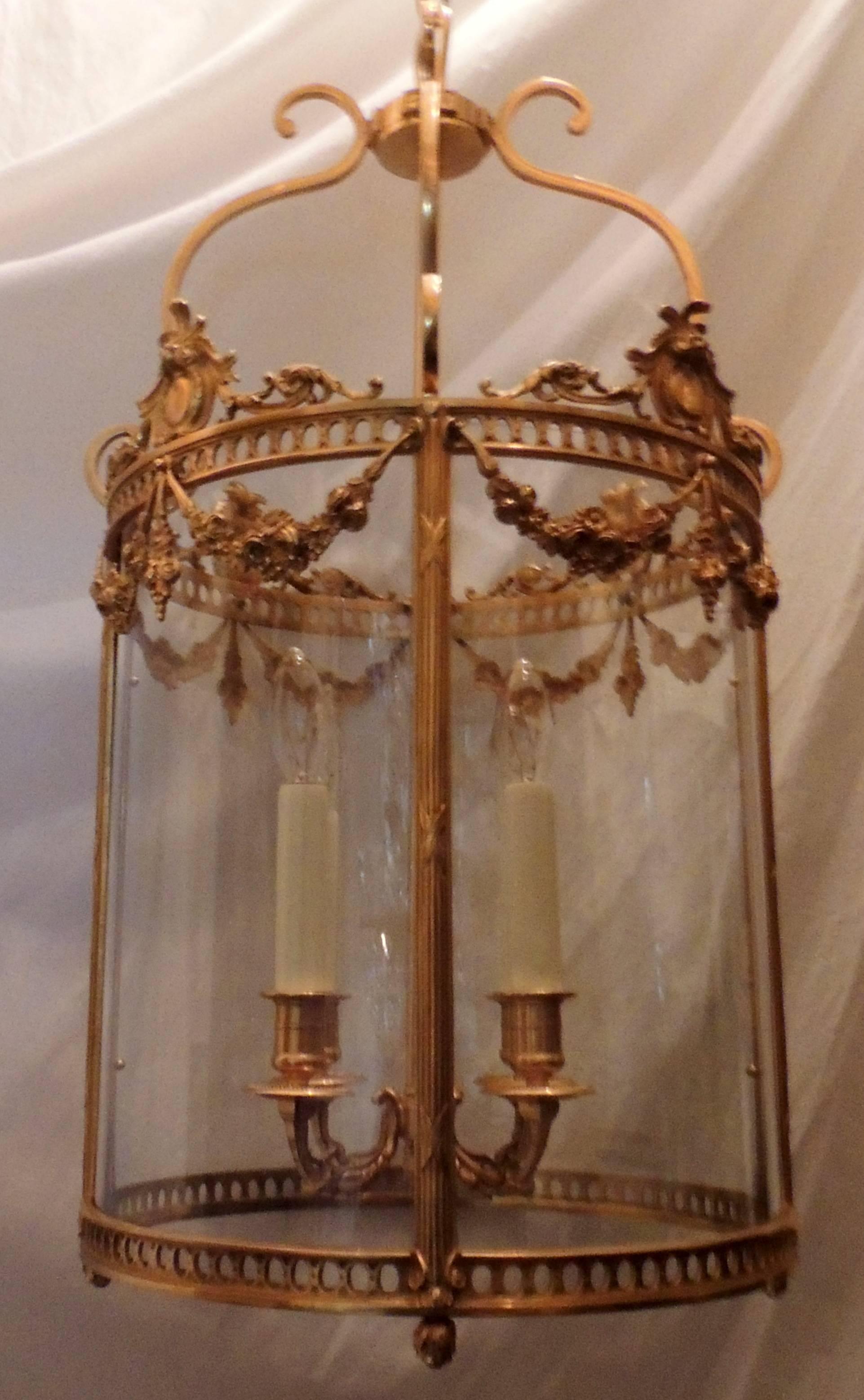 A wonderful French ormolu-mounted doré gilt bronze floral swag and crest top four-light rounded glass lantern chandelier fixture.