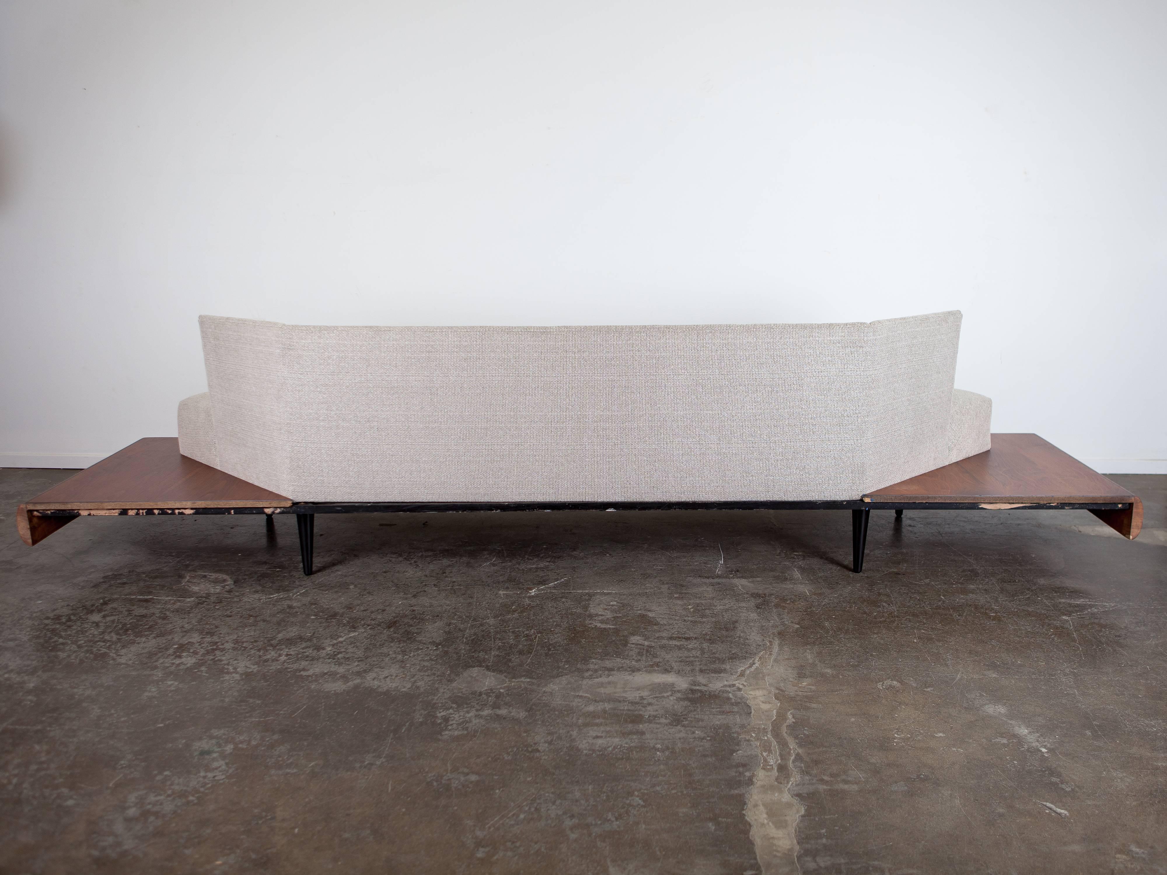 This sleek sofa was designed by Mid-Century Modern legend Adrian Pearsall. The platform base is in walnut fabrication and the sofa has been updated in woven neutral upholstery.