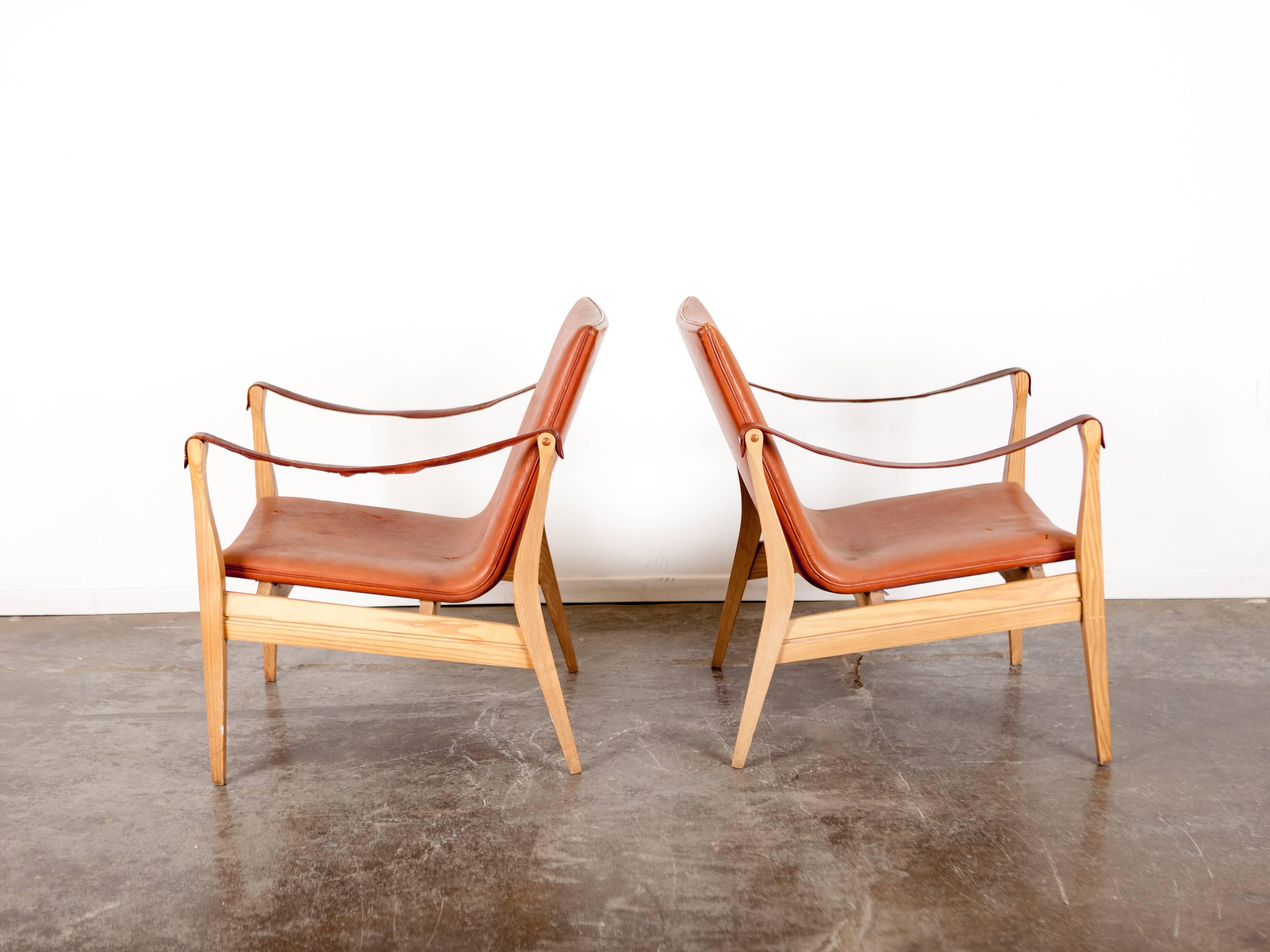 Rare pair of Ebbe & Karen Clemmensen. Safari chairs with original brown leather and an ash frame. Model 4305, designed in 1958, Danish, produced by Fritz Hansen. Some wear and a few small tears in one of the chairs which has been repaired.