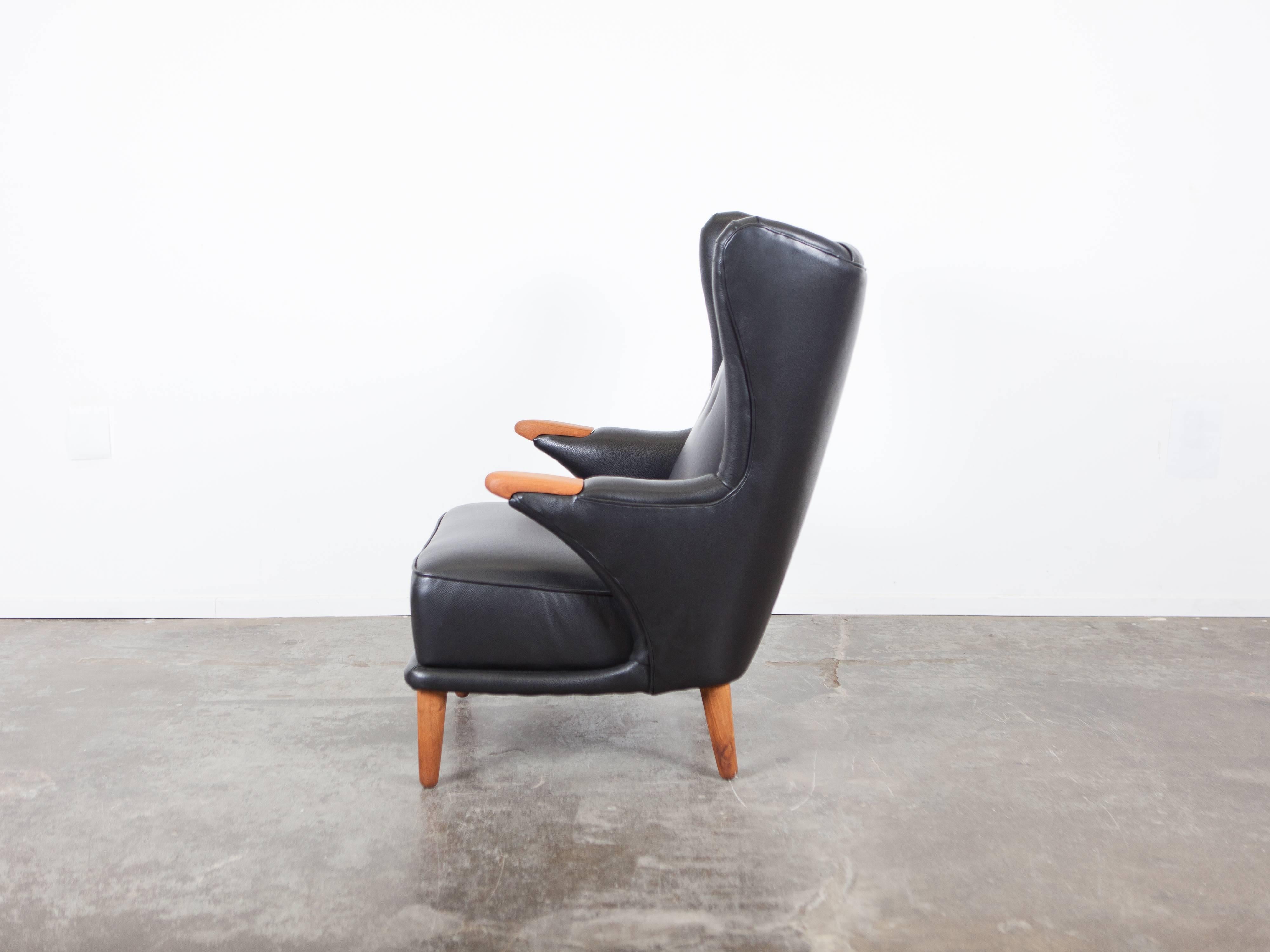Danish Mid-Century Modern lounge chair, designed by Svend Skipper with oak arm inserts, newly upholstered in black leather with tufted back.