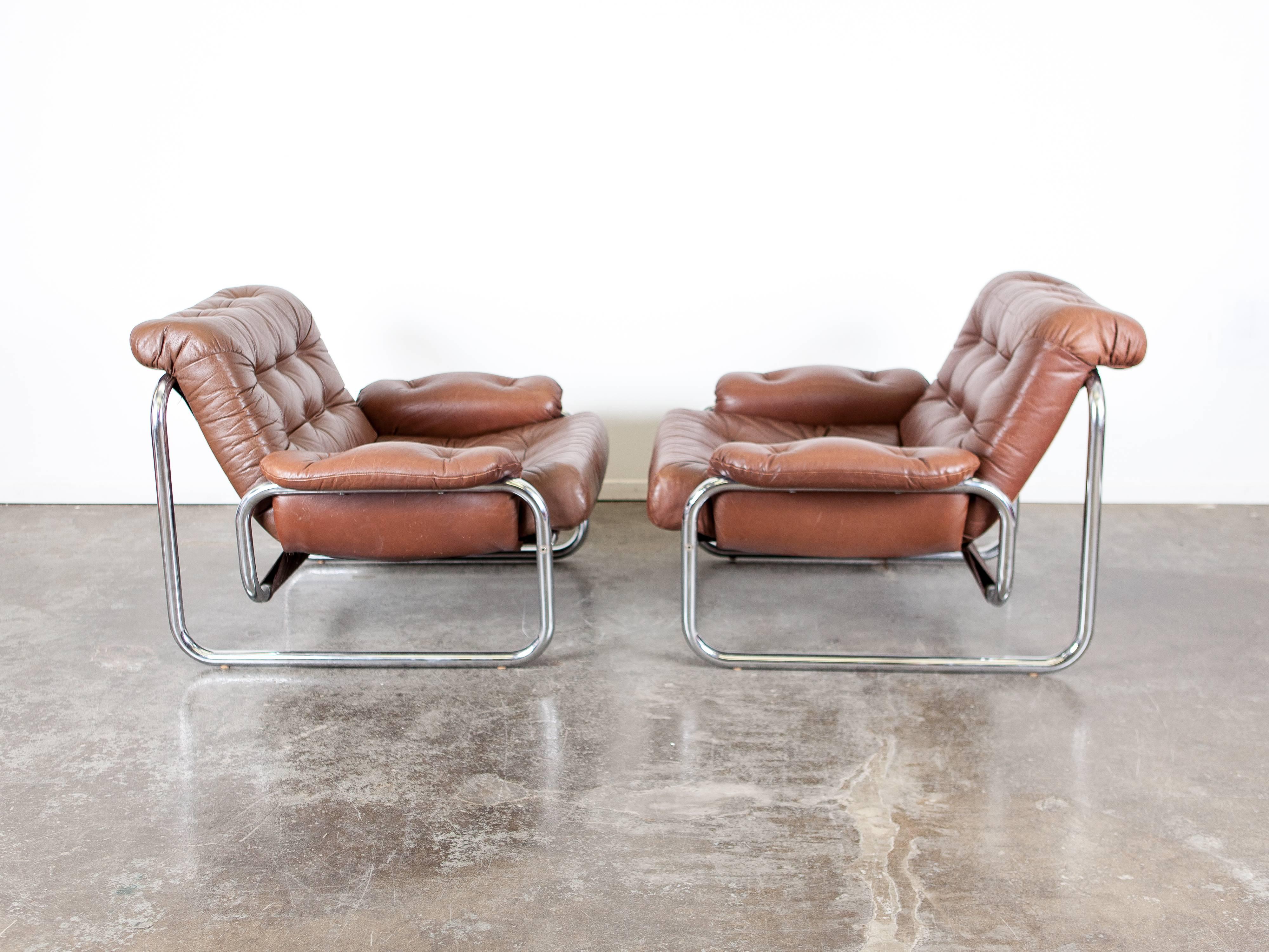 Pair of Swedish, 1970s tubular metal framed lounge chairs with original brown tufted cushion and armrests. Produced by Ikea, model troligen, designed by Johan Bertil Häggström.

  