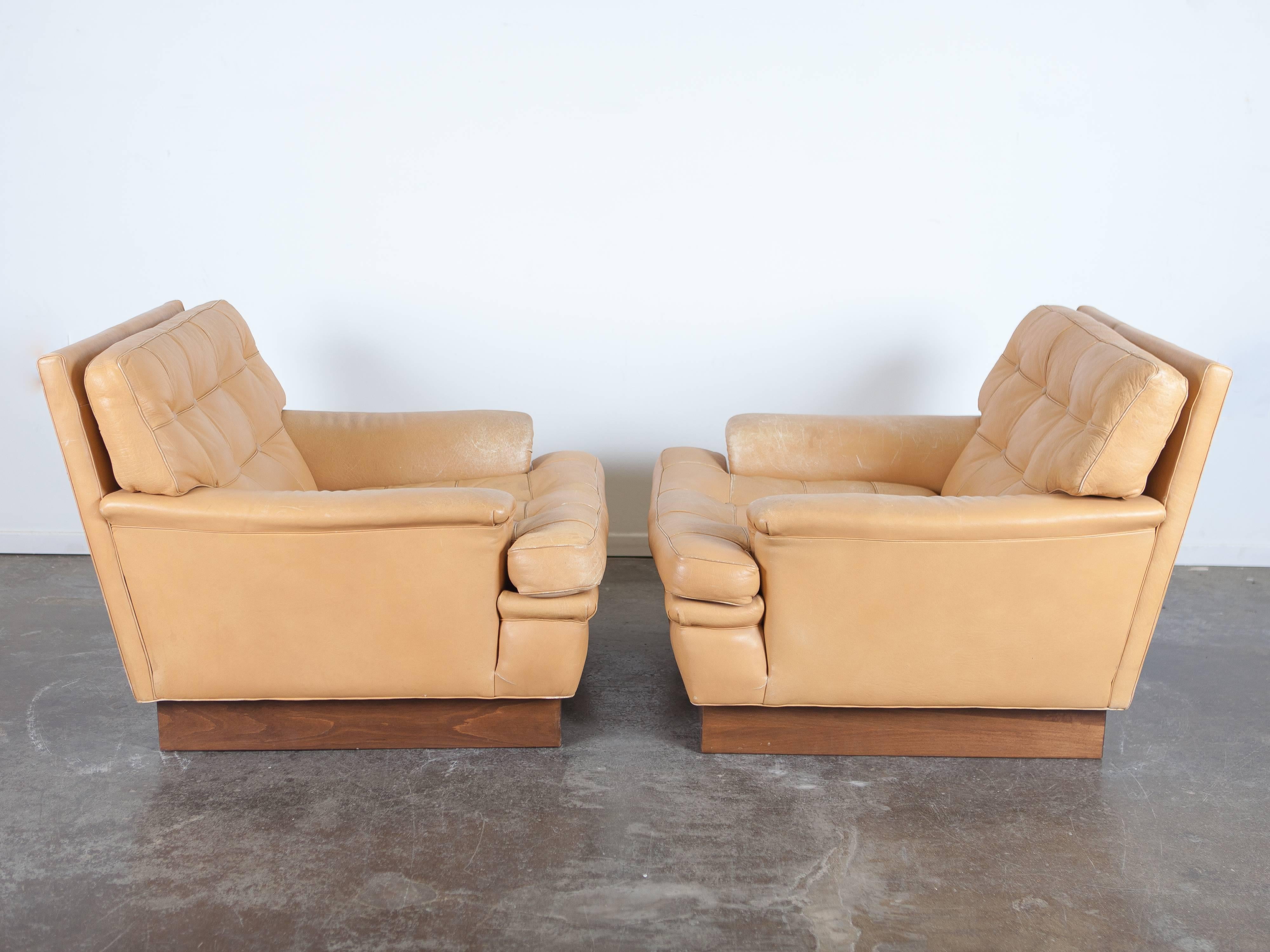 Pair of tan leather lounge chairs on plinth base, model Merkur, designed by Arne Norell and produced by Norell AB of Sweden.