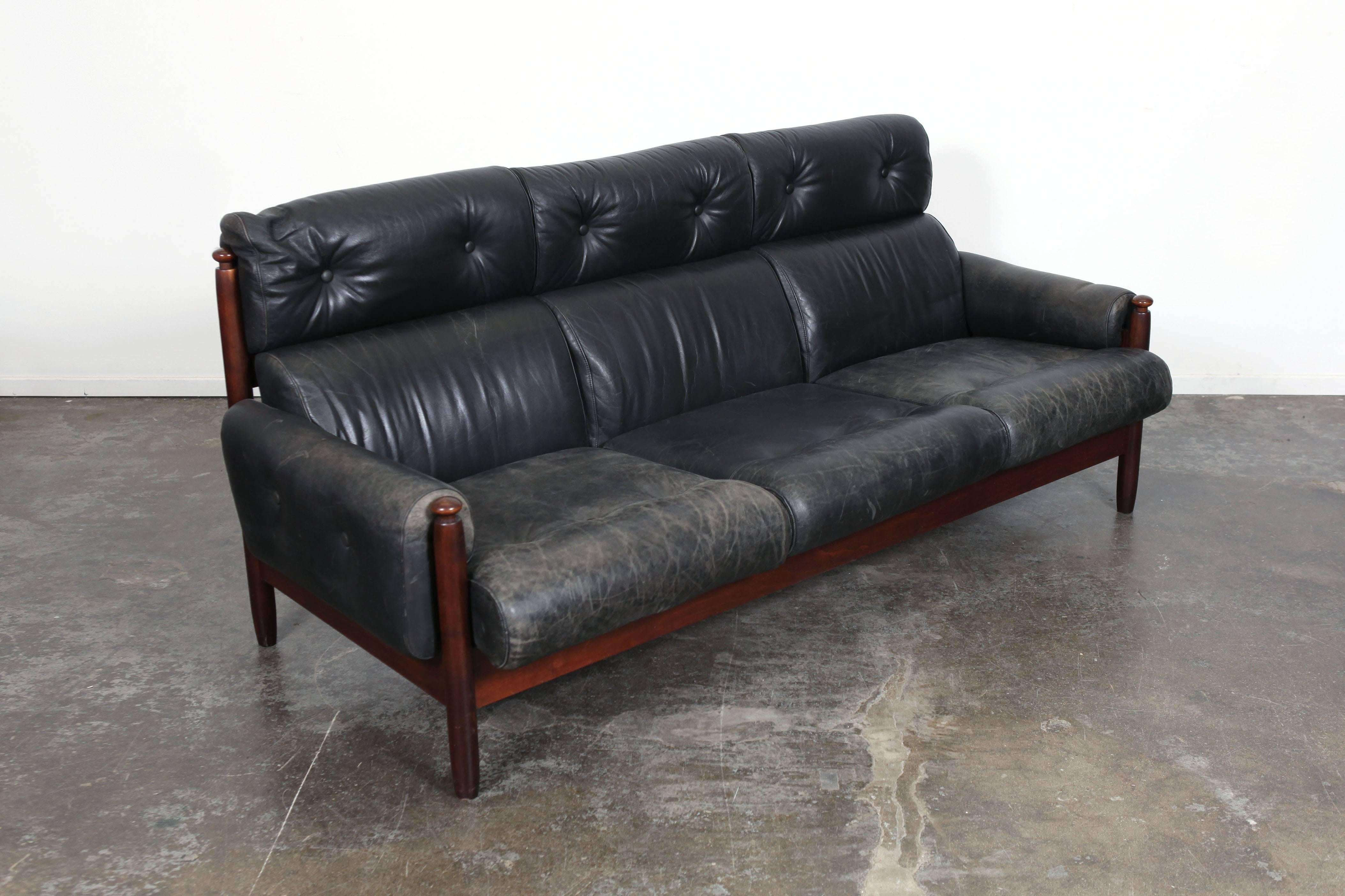 Swedish Mid-Century Modern black leather sofa with double button tufted head rests, three seats, solid wood frame and arms. Leather is beautifully aged with great patina.