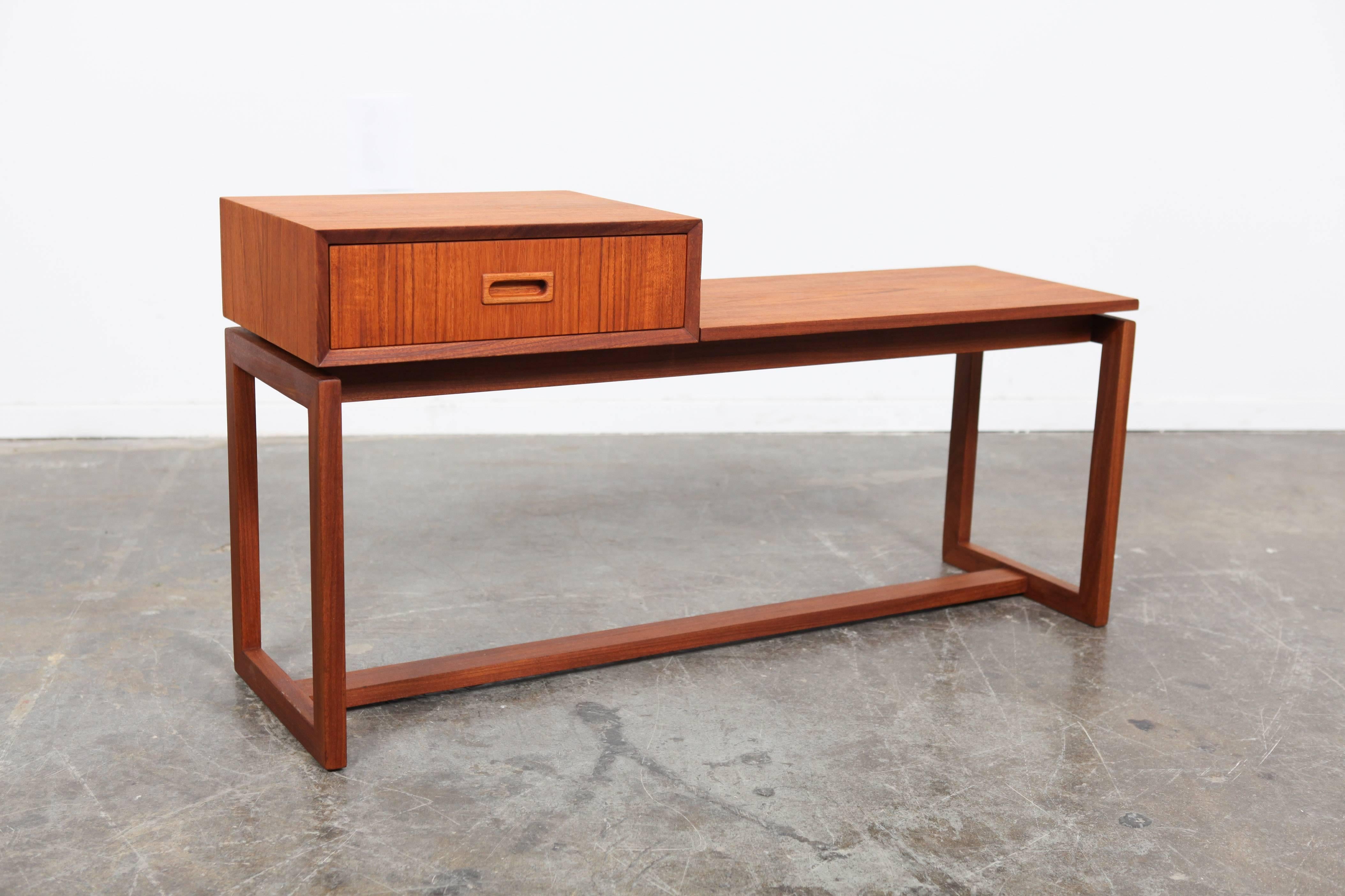 Danish Mid-Century Modern Teak asymmetrical end table with single drawer, recessed oblong pull and supporting H-stretcher.