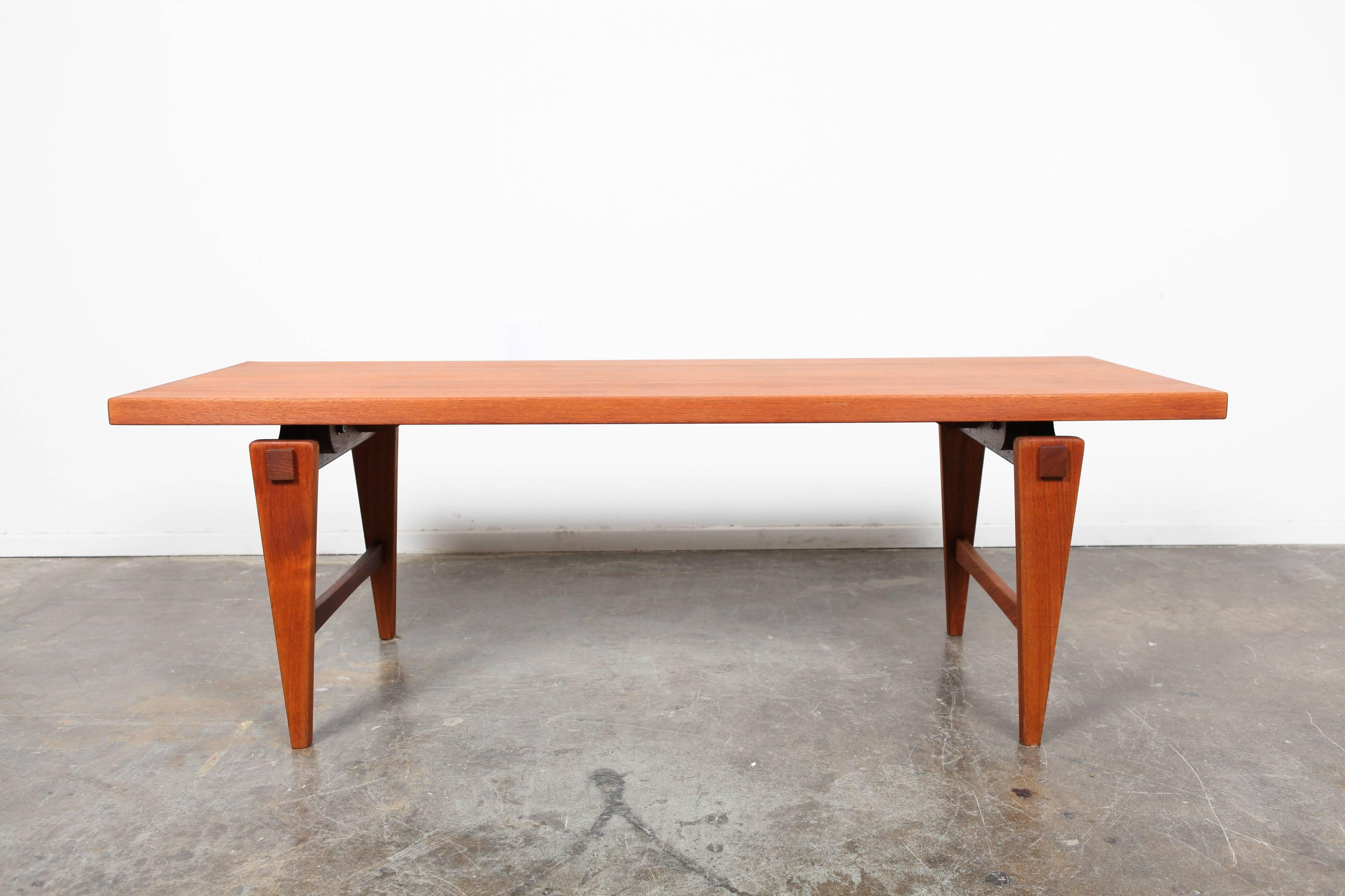 Incredible Mid-Century Modern coffee table with a floating style top and tapered legs. This piece has two side stretchers and square peg detailing on the legs.