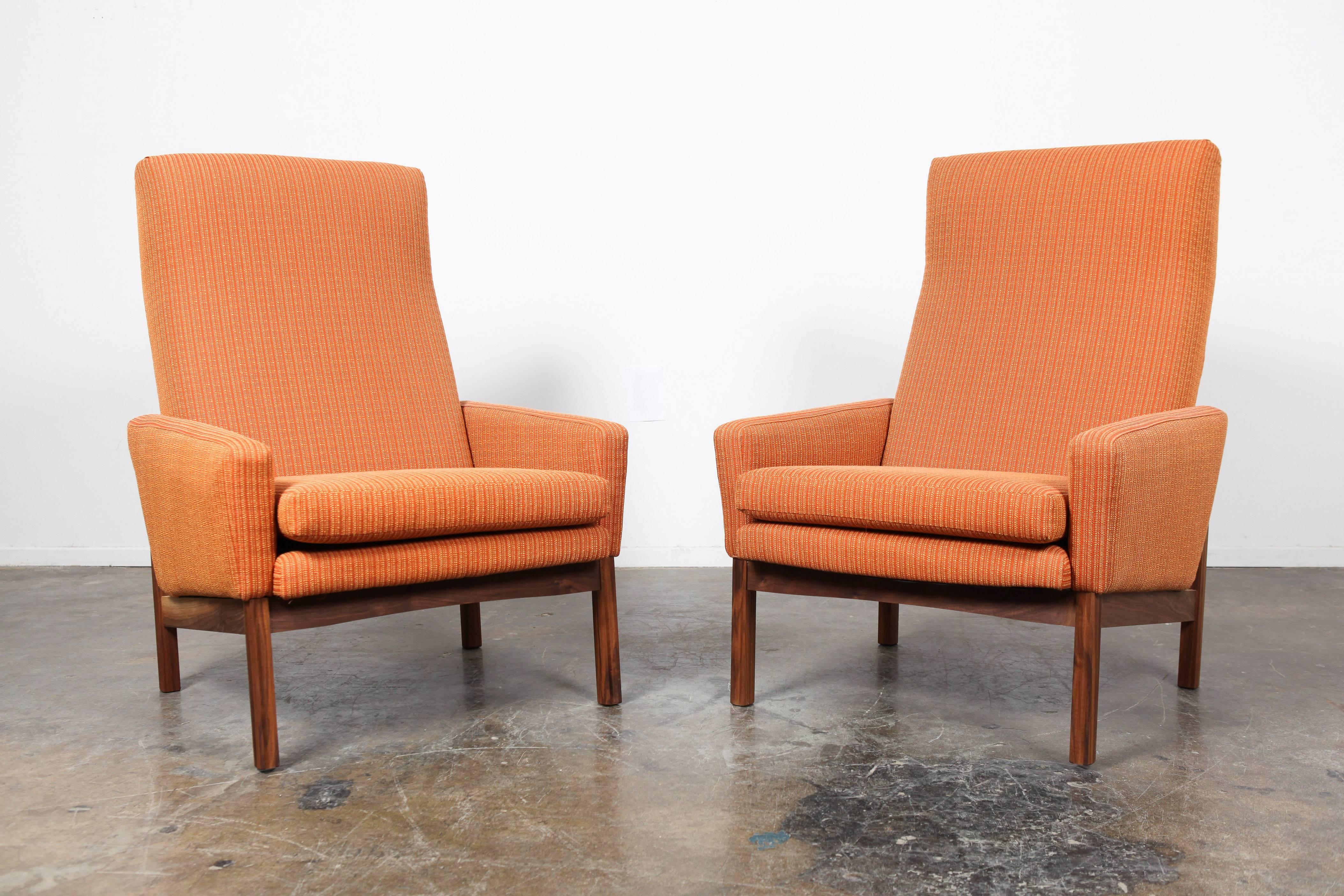 Pair of reupholstered Mid-Century Modern Danish tall-back lounge chairs with newly produced tilted walnut base.