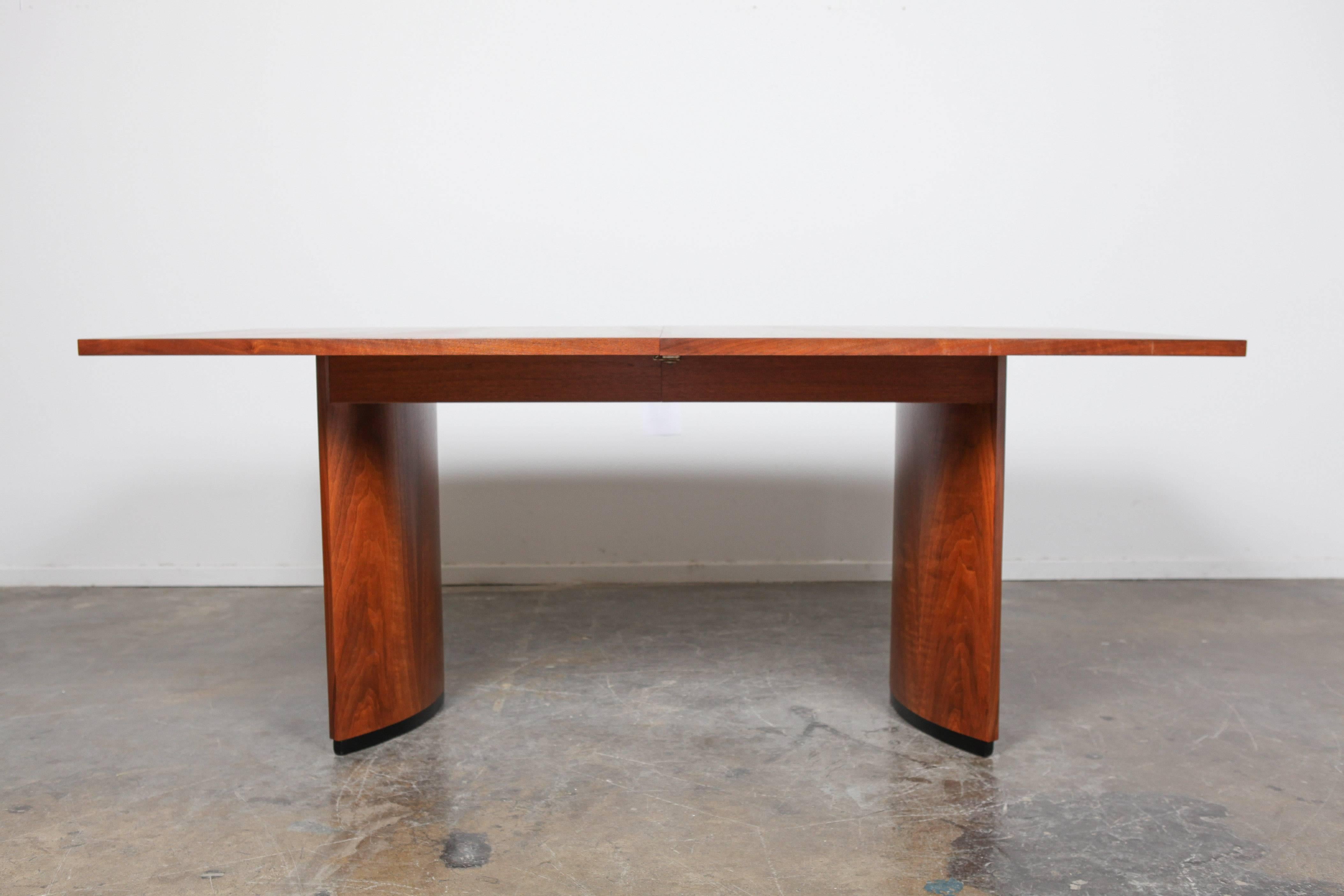 Beautiful, large Mid-Century Modern walnut dining table with excellent grain throughout. this piece has a surfboard shaped top and sits on two pedestal/inset curved legs. The table comes with 2 extensions, each that are 42