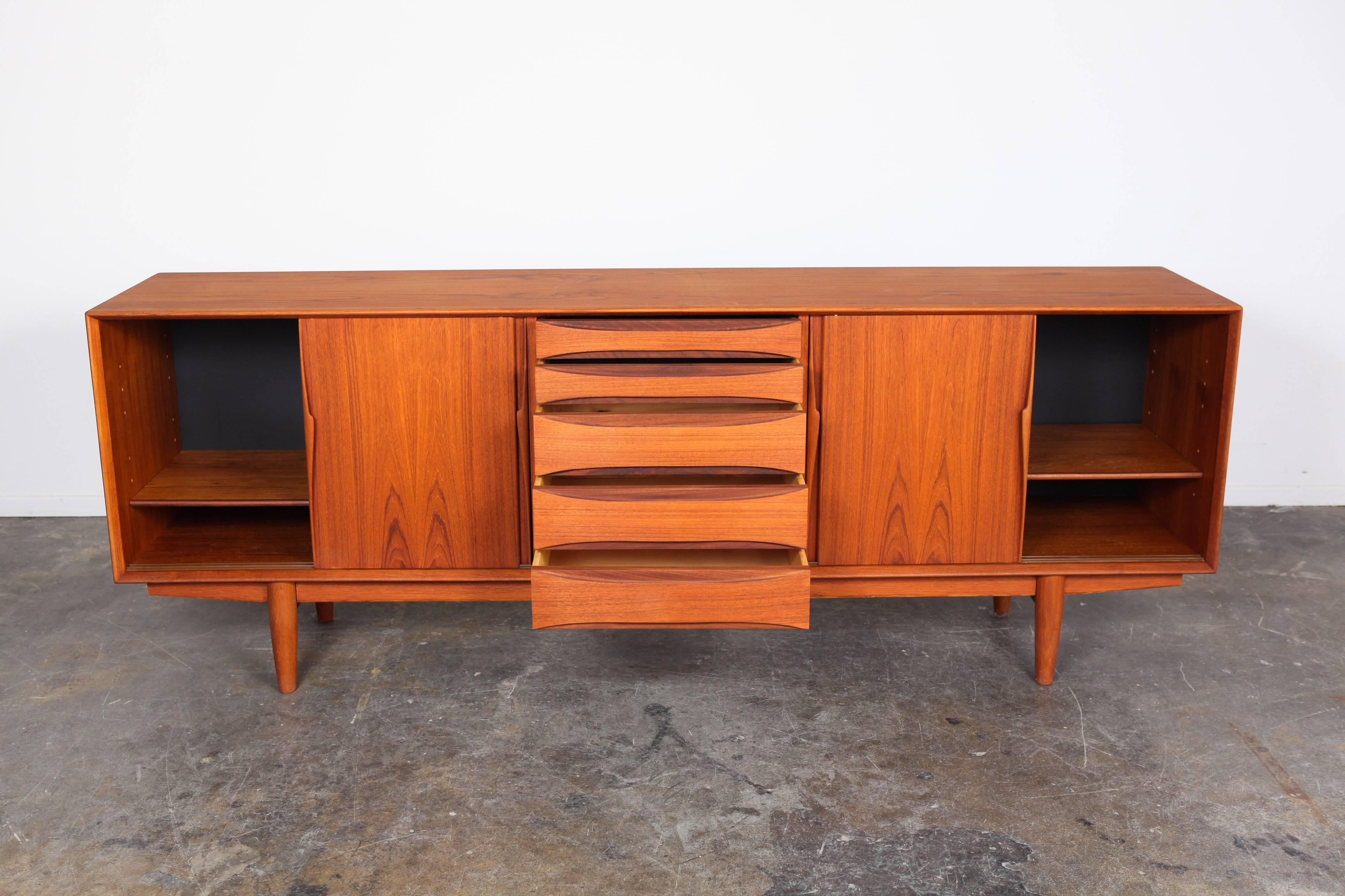 Mid-Century Danish teak sideboard by Dyrlund with five centre sculptural drawers and four sliding doors.