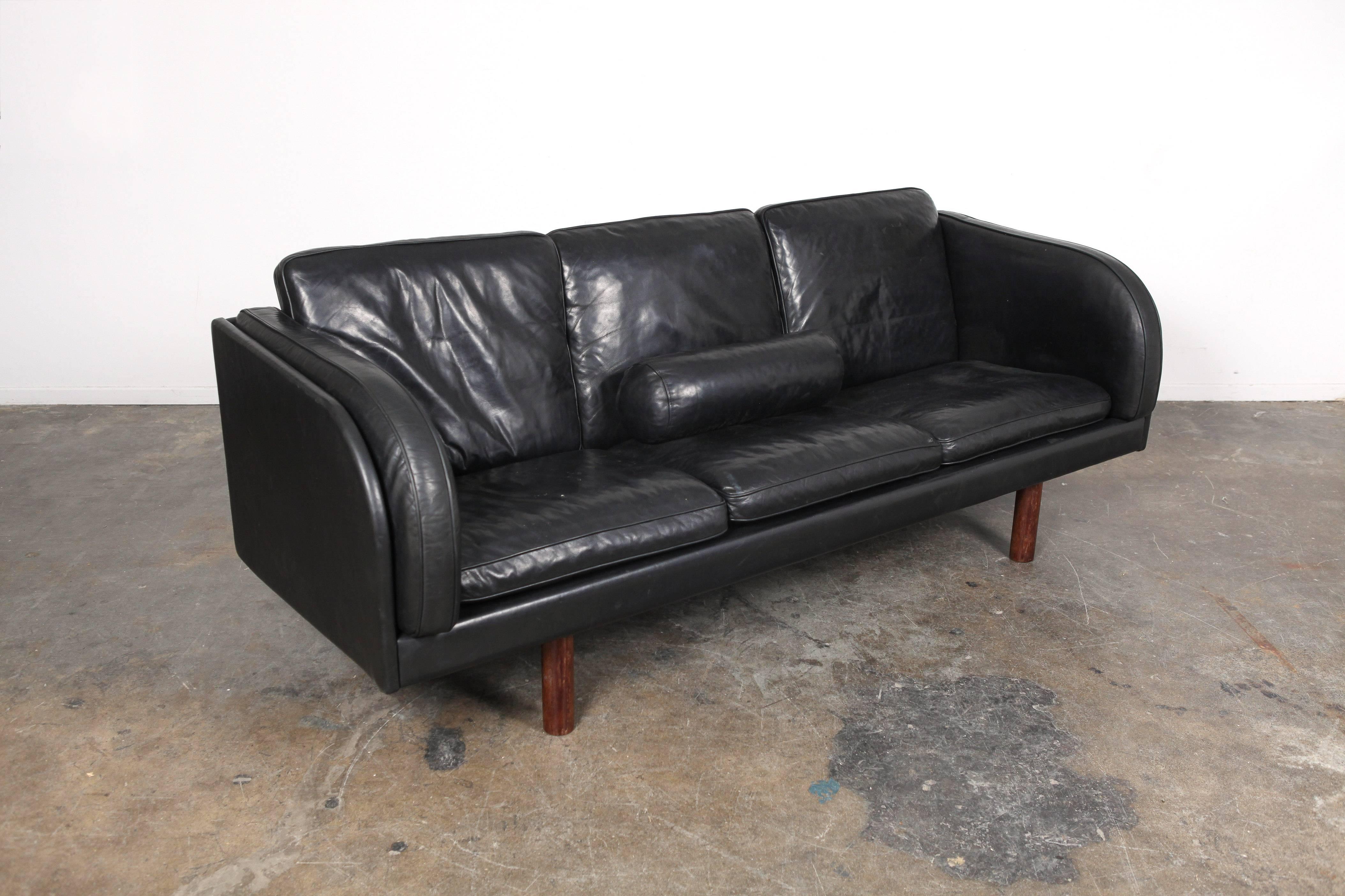 Rare Danish black leather three-seat sofa designed by Jørgen Gammelgaard, produced by Erik Jørgensen. This sofa features loose seat and back cushions, as we as a single bolster pillow and cylindrical wooden legs.