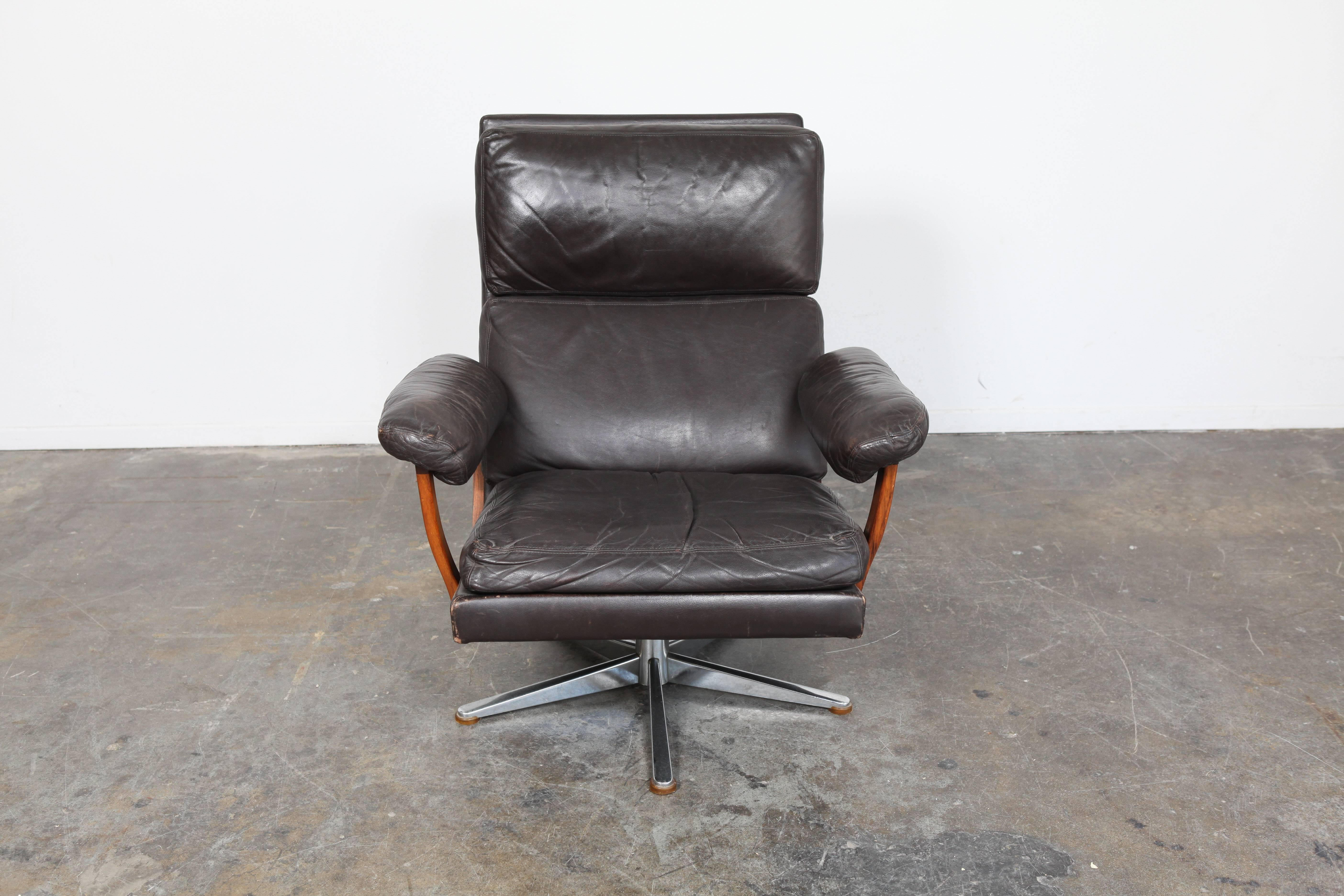 Danish Mid-Century Modern dark brown leather lounge chair with chrome base and padded rosewood arms.