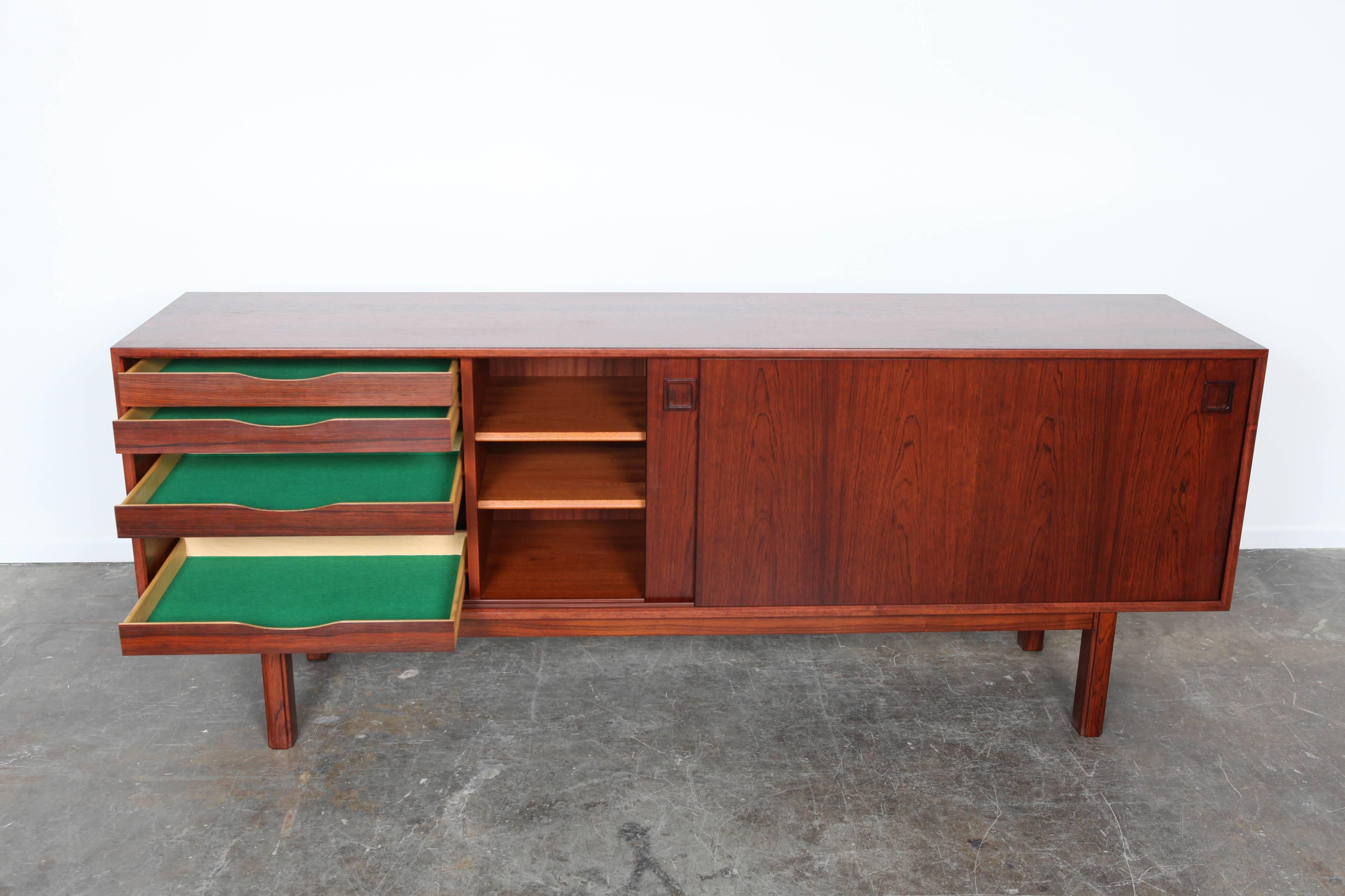 Long, low Danish rosewood sideboard by Gunni Omann with two sliding doors and adjustable interior shelving, solid rosewood legs and door handles. Recently refinished.