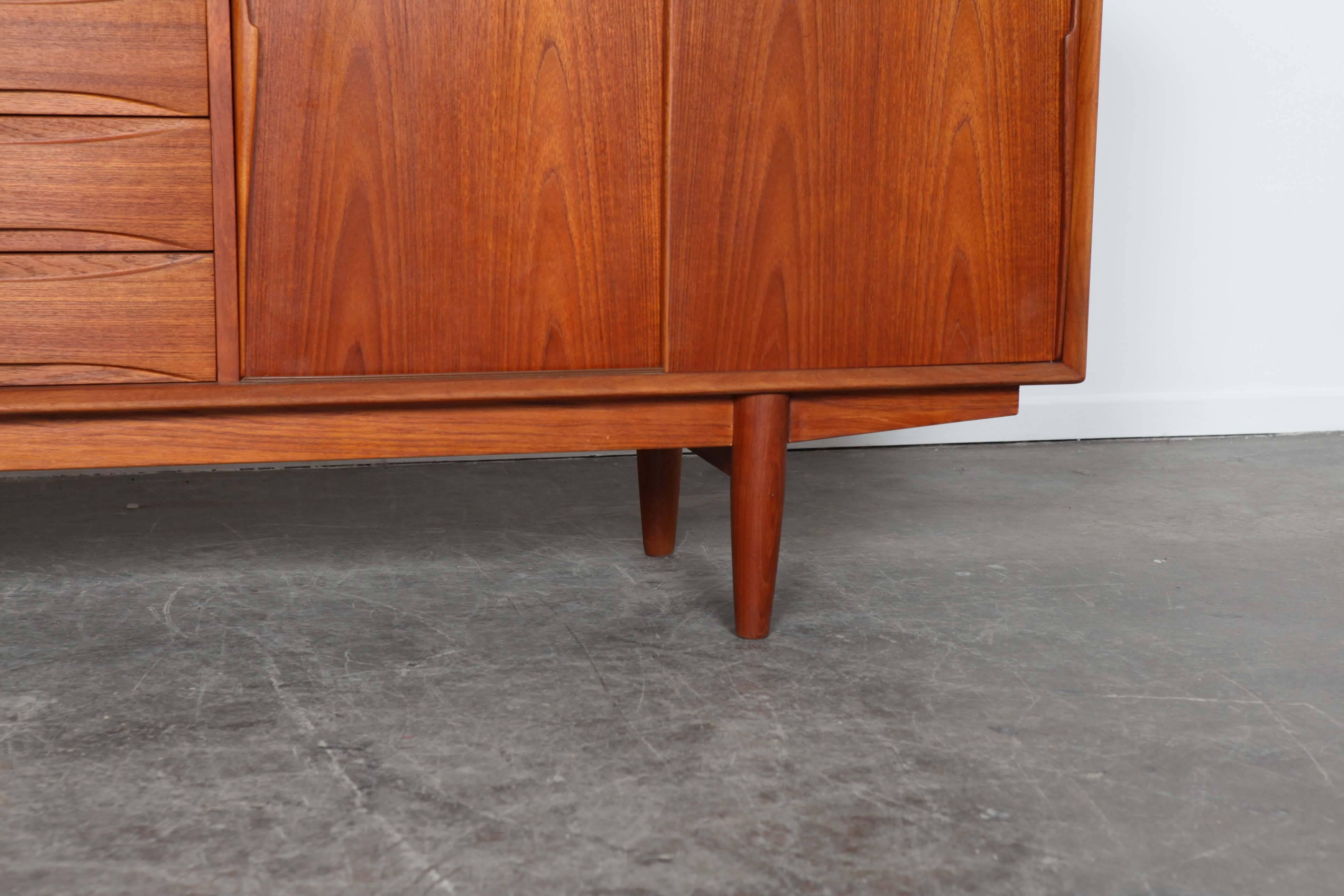 Mid-Century teak sideboard with four sliding doors and four pull-out drawers. Made by Dyrlund, Denmark. Newly refinished.